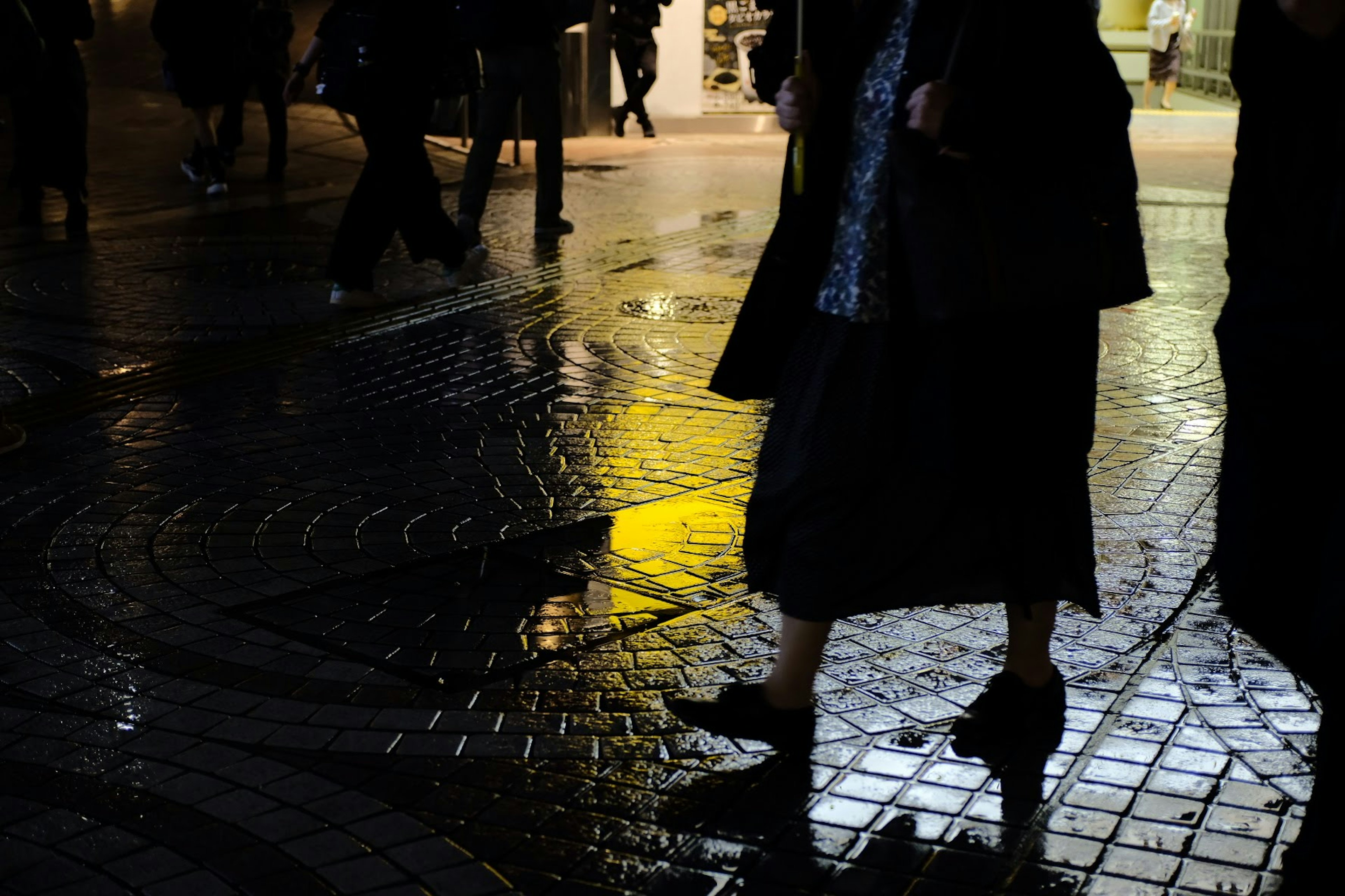 人們在雨水浸濕的街道上夜間行走