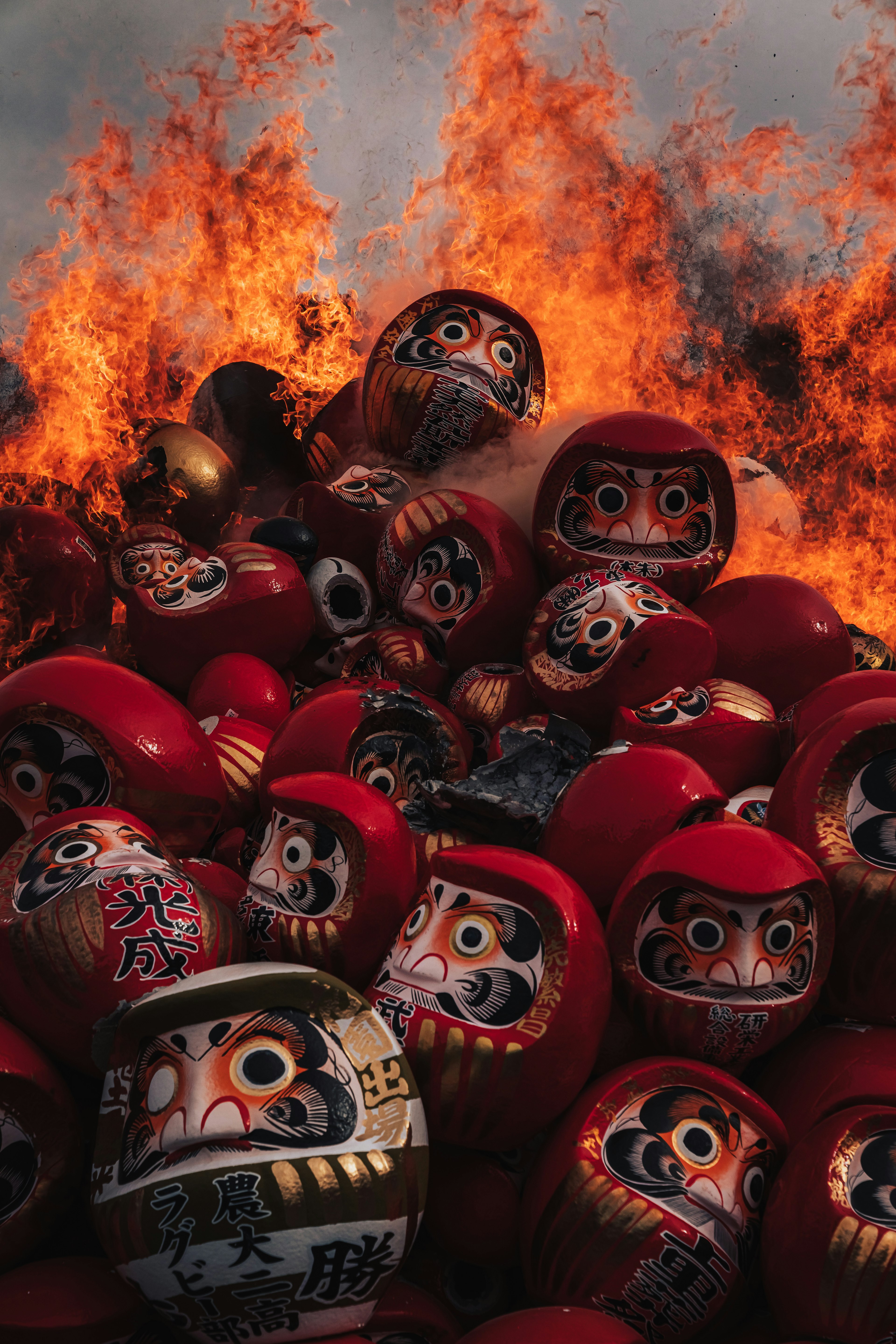 A pile of red Daruma dolls engulfed in flames