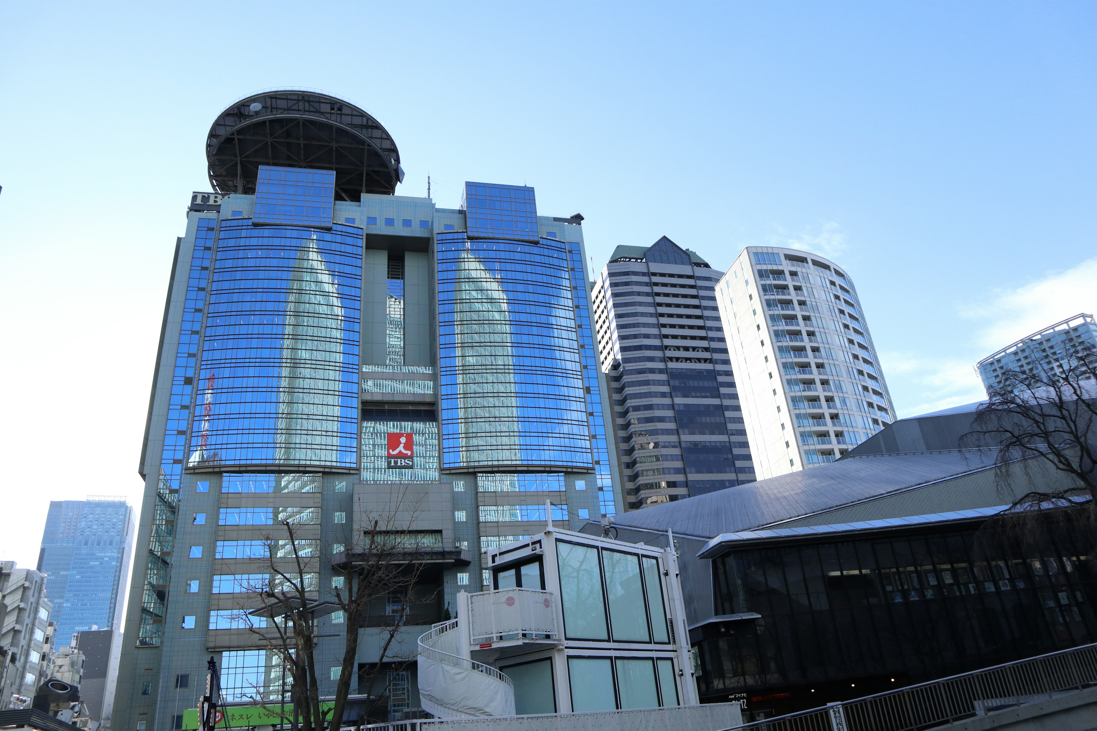 Modern skyscraper with glass facade surrounded by other buildings under a clear blue sky