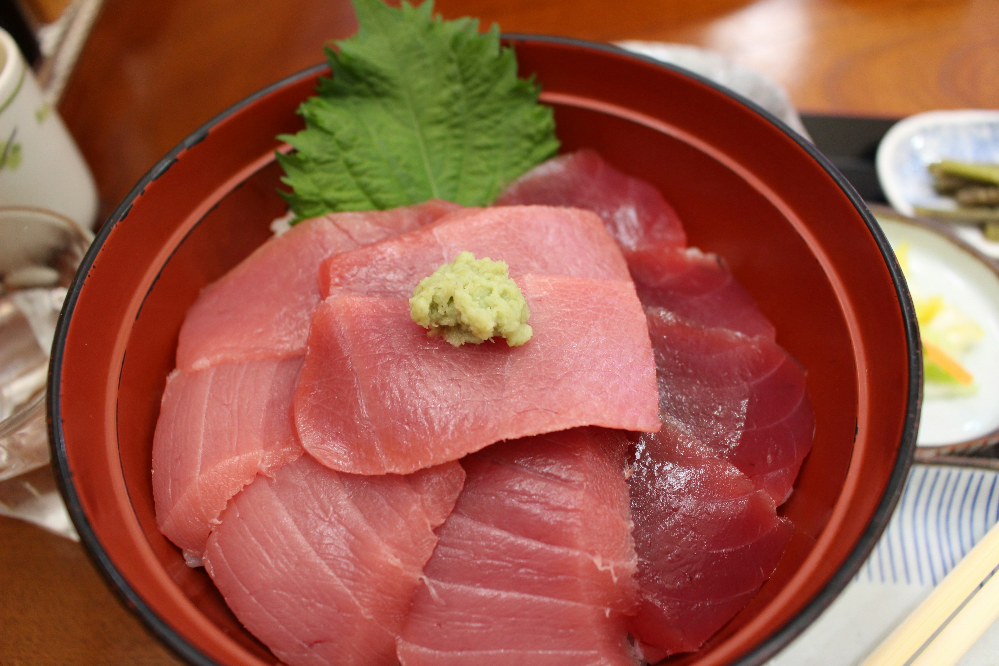 Semangkuk sashimi tuna campuran yang dihiasi wasabi dan daun shiso