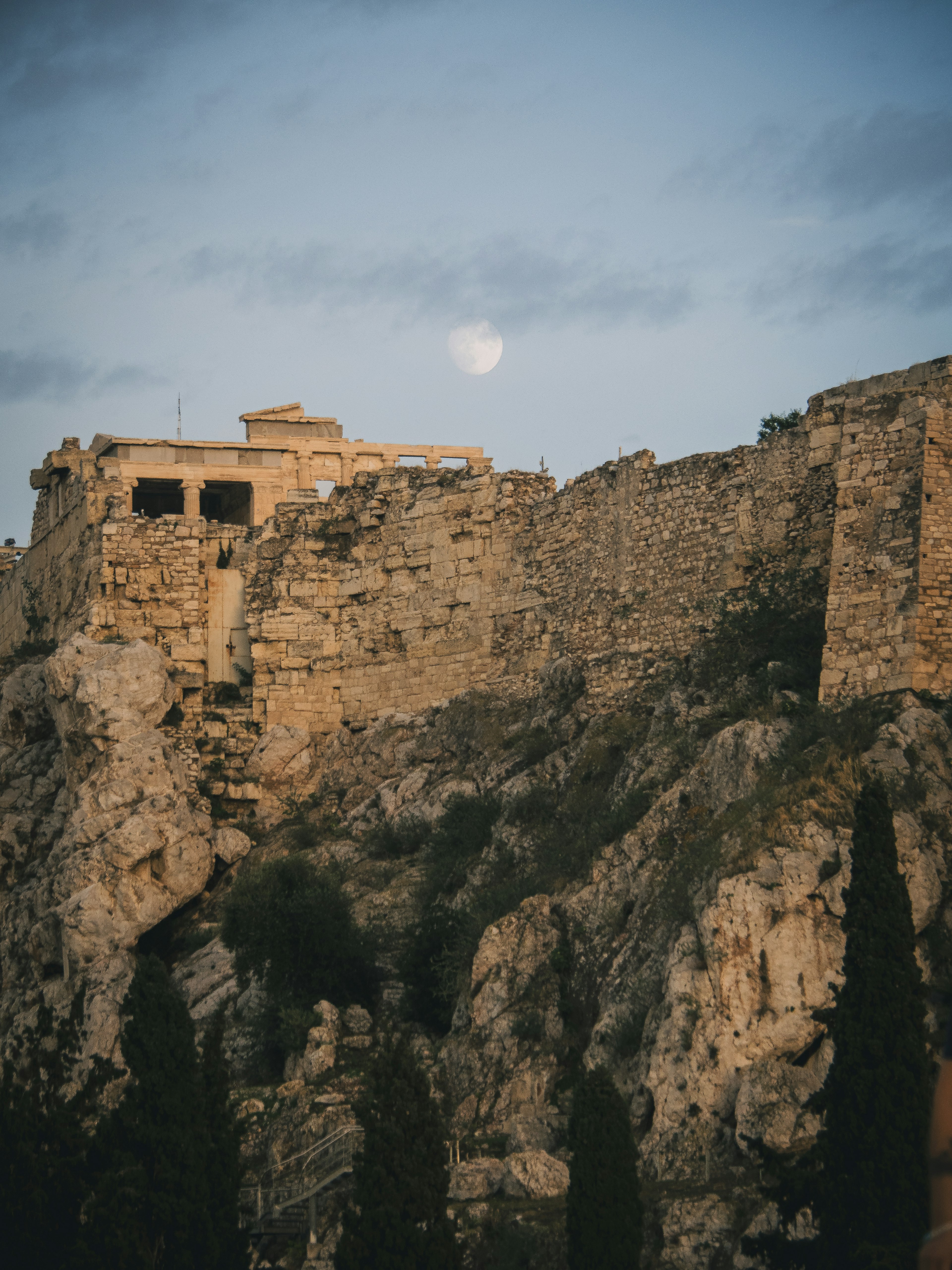 Ancient ruins at dusk with a visible moon