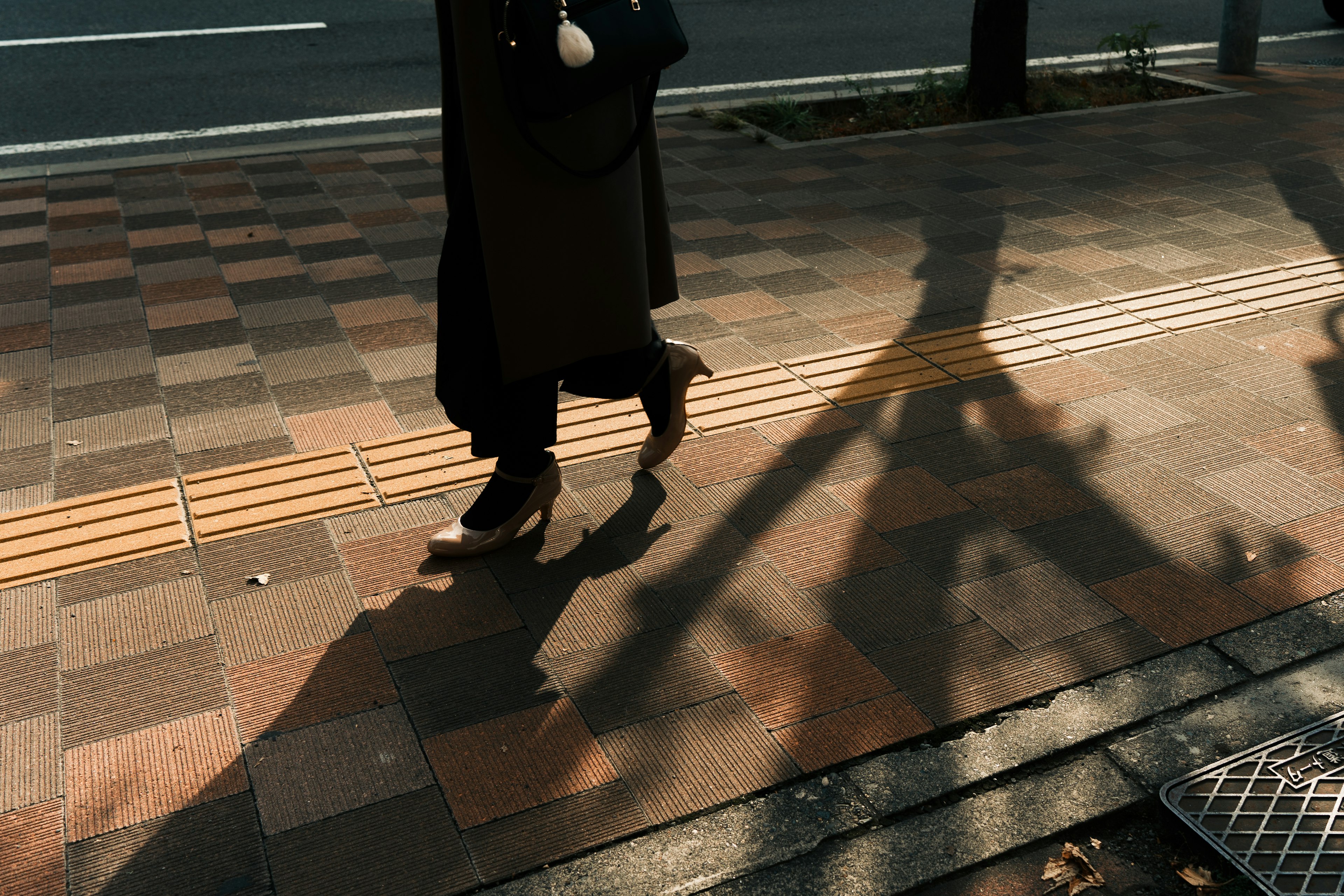 Une personne marchant sur un trottoir avec de longues ombres projetées