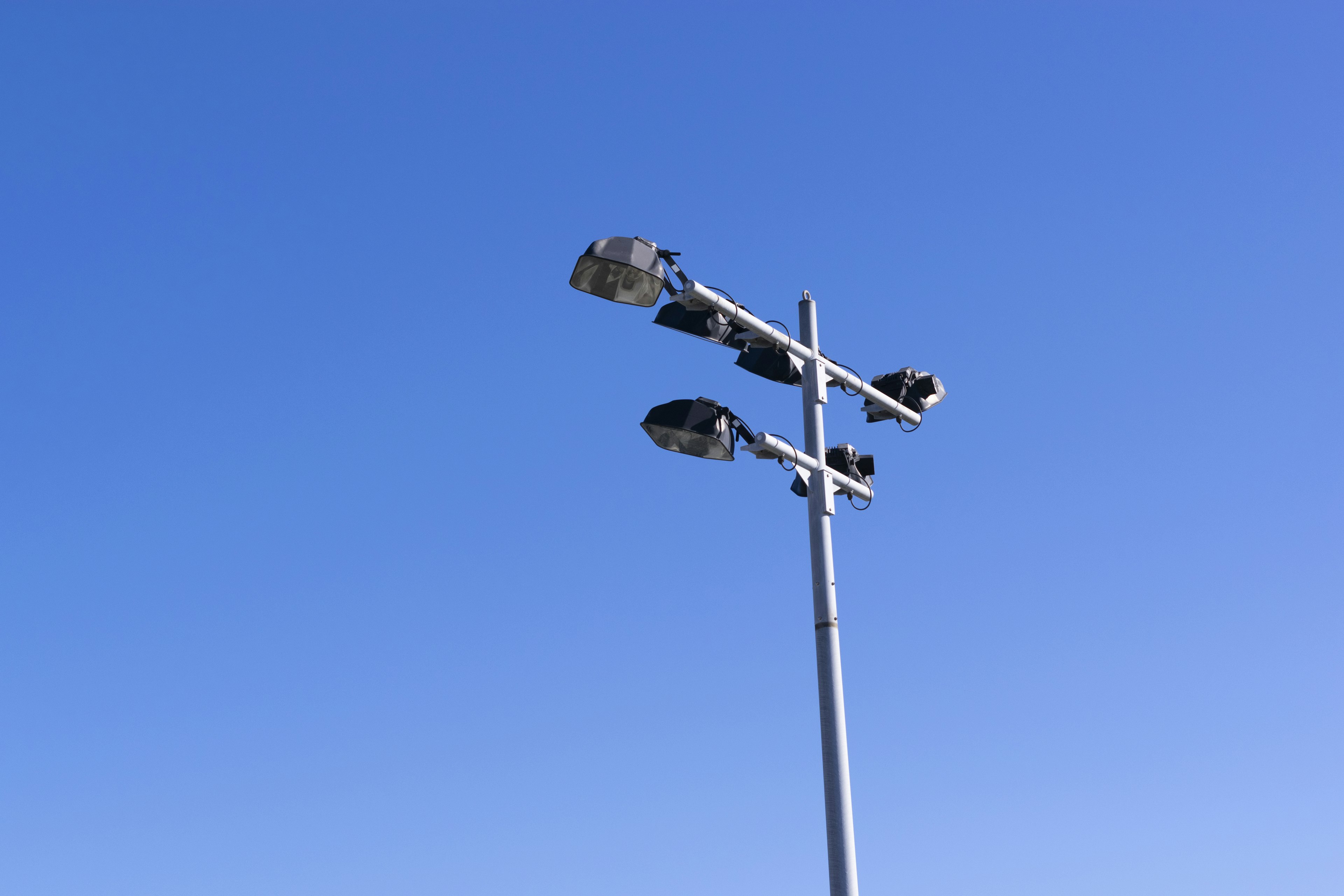 Straßenlaterne und Überwachungskameras auf einem Mast unter einem klaren blauen Himmel