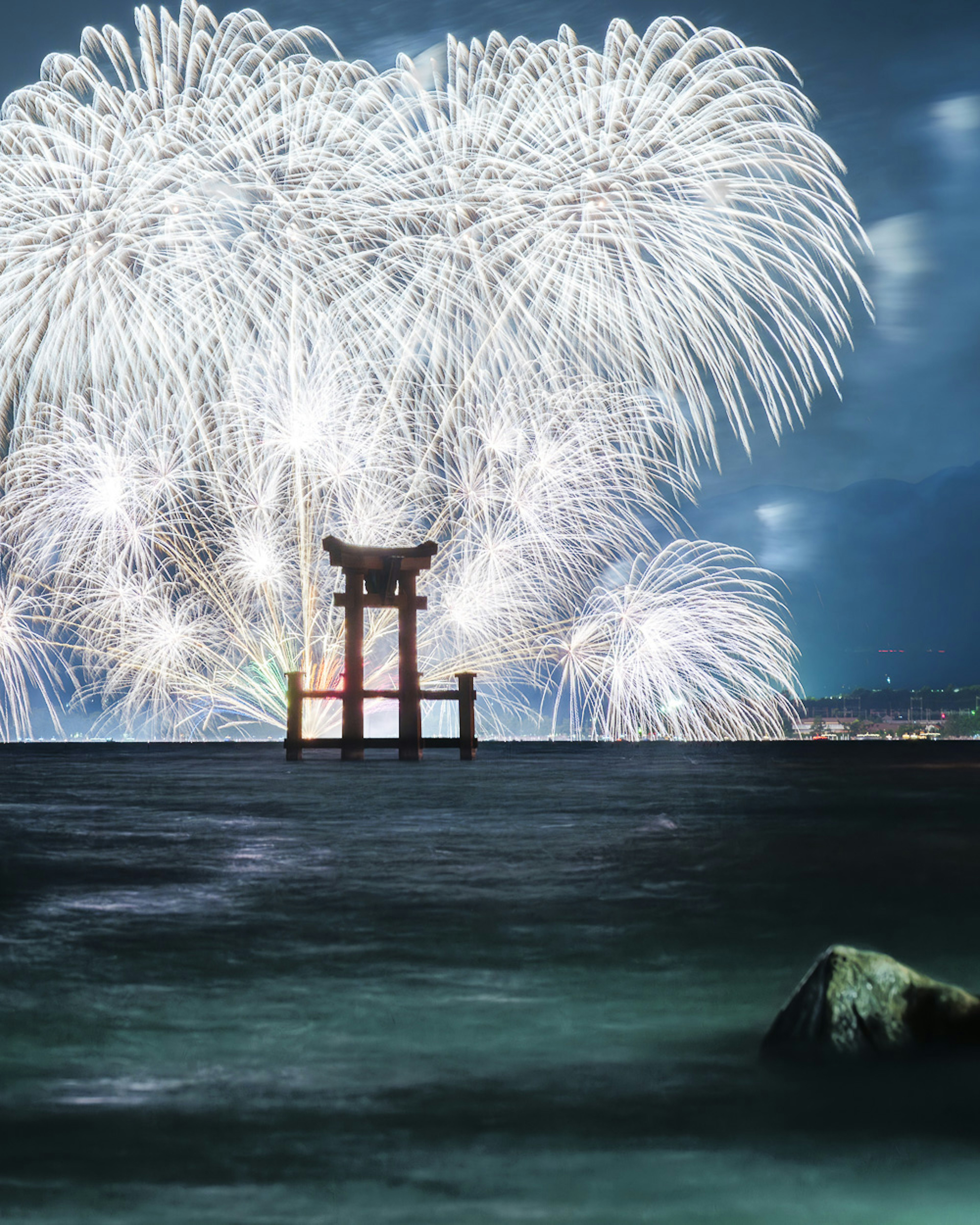 海の上に立つ鳥居と花火の美しい夜景