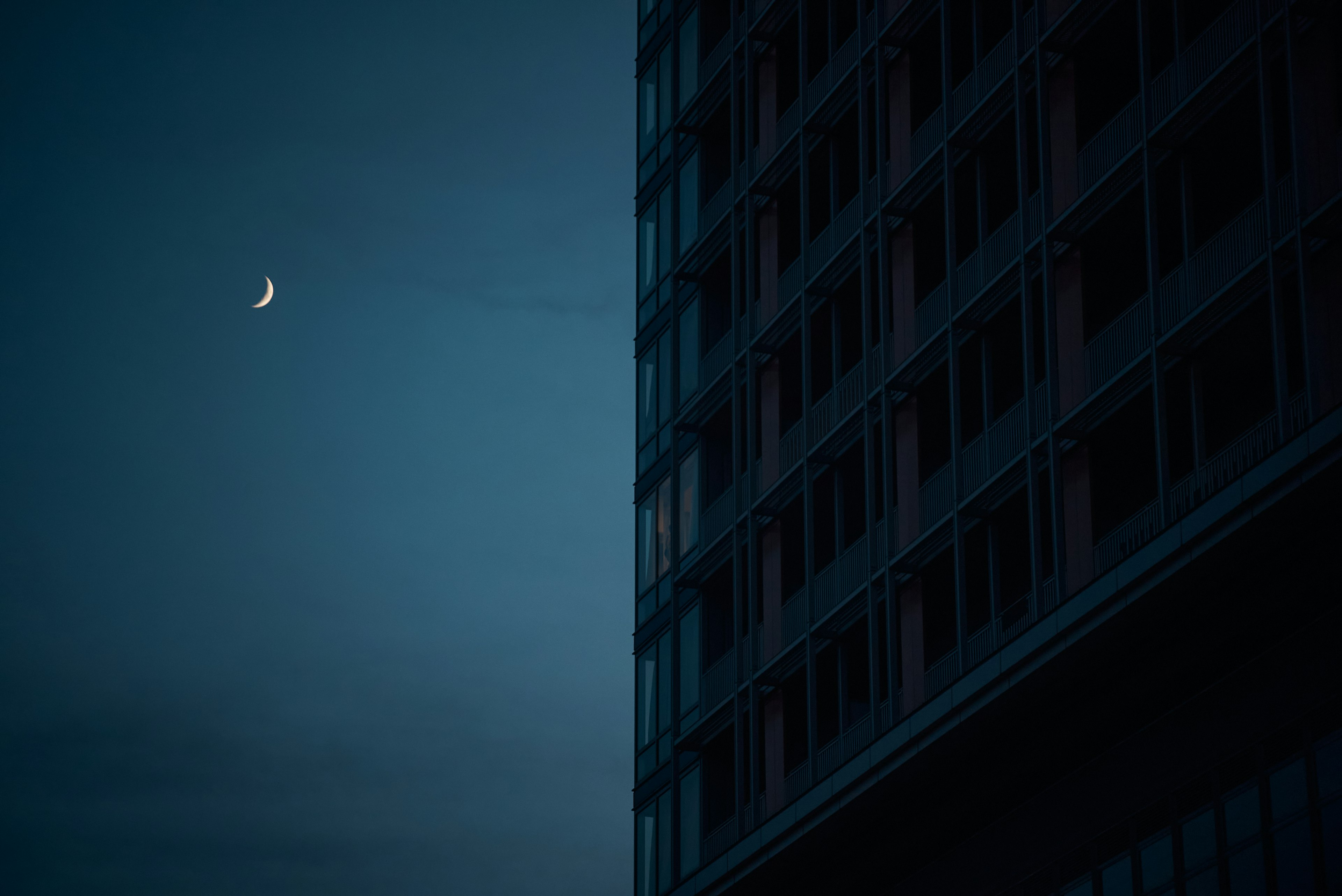 Crescent moon in a dark sky beside a building corner