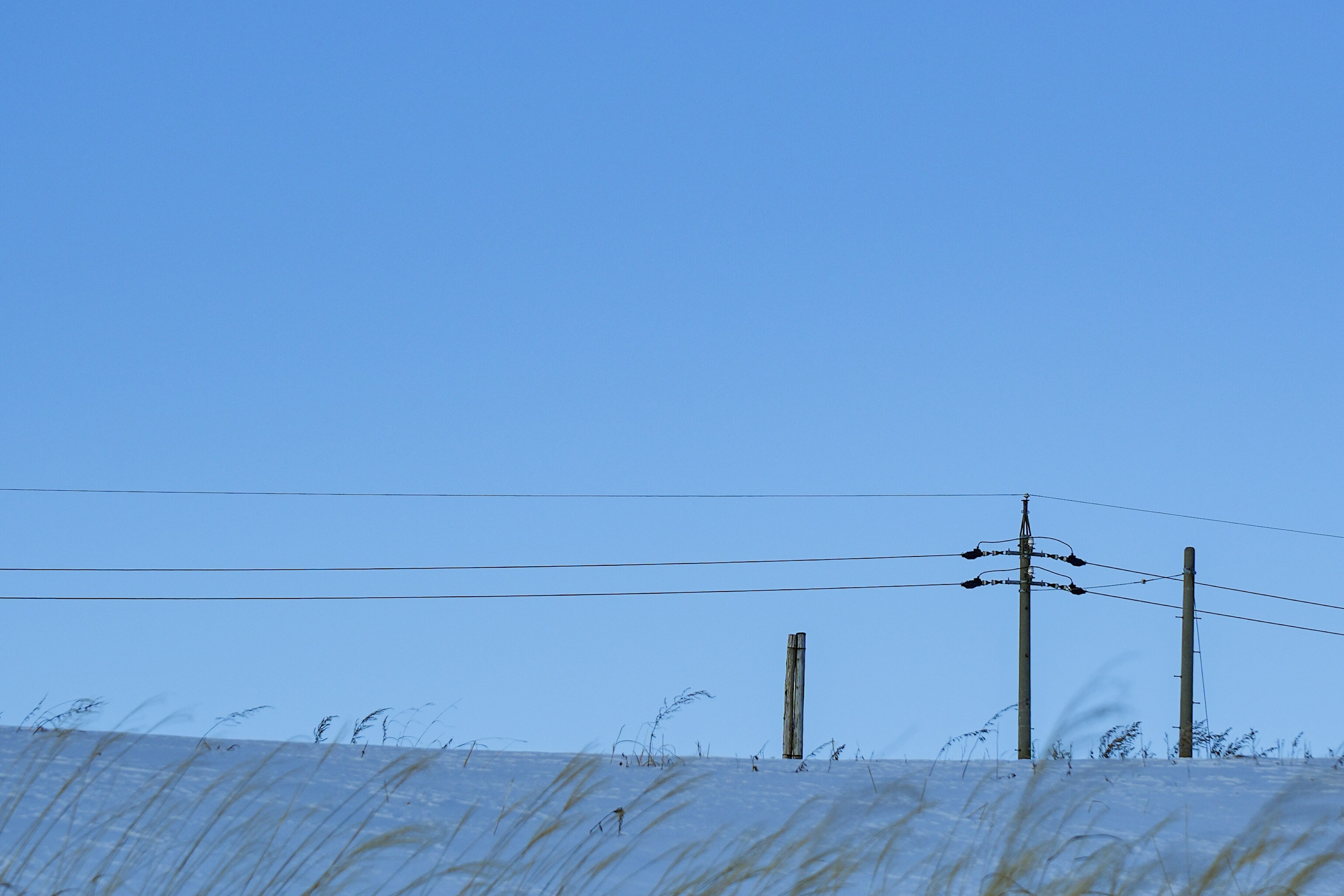 Landschaftsfoto mit klarem blauen Himmel und Strommasten