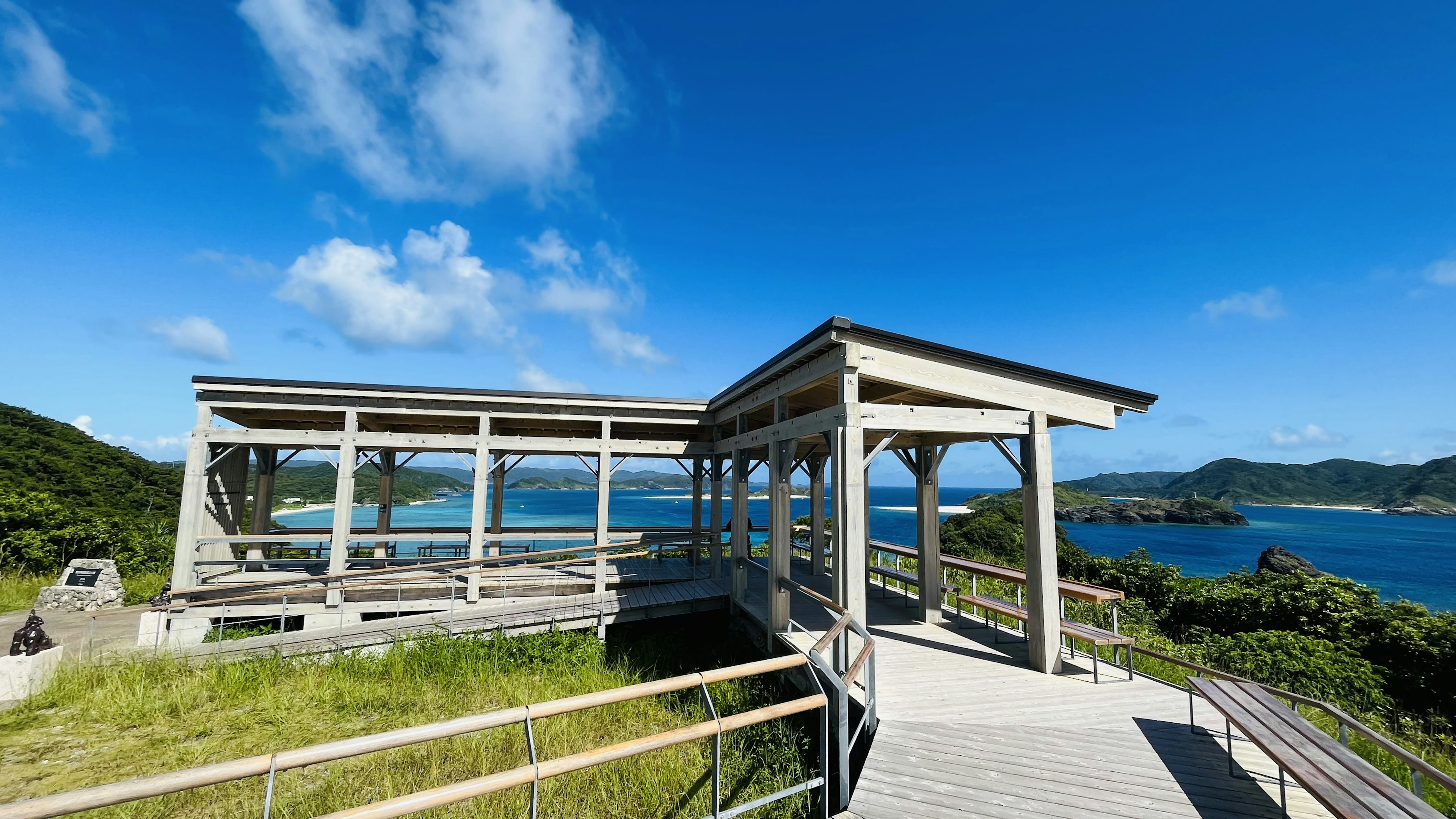 Belvédère en bois sous un ciel bleu avec un paysage vert environnant