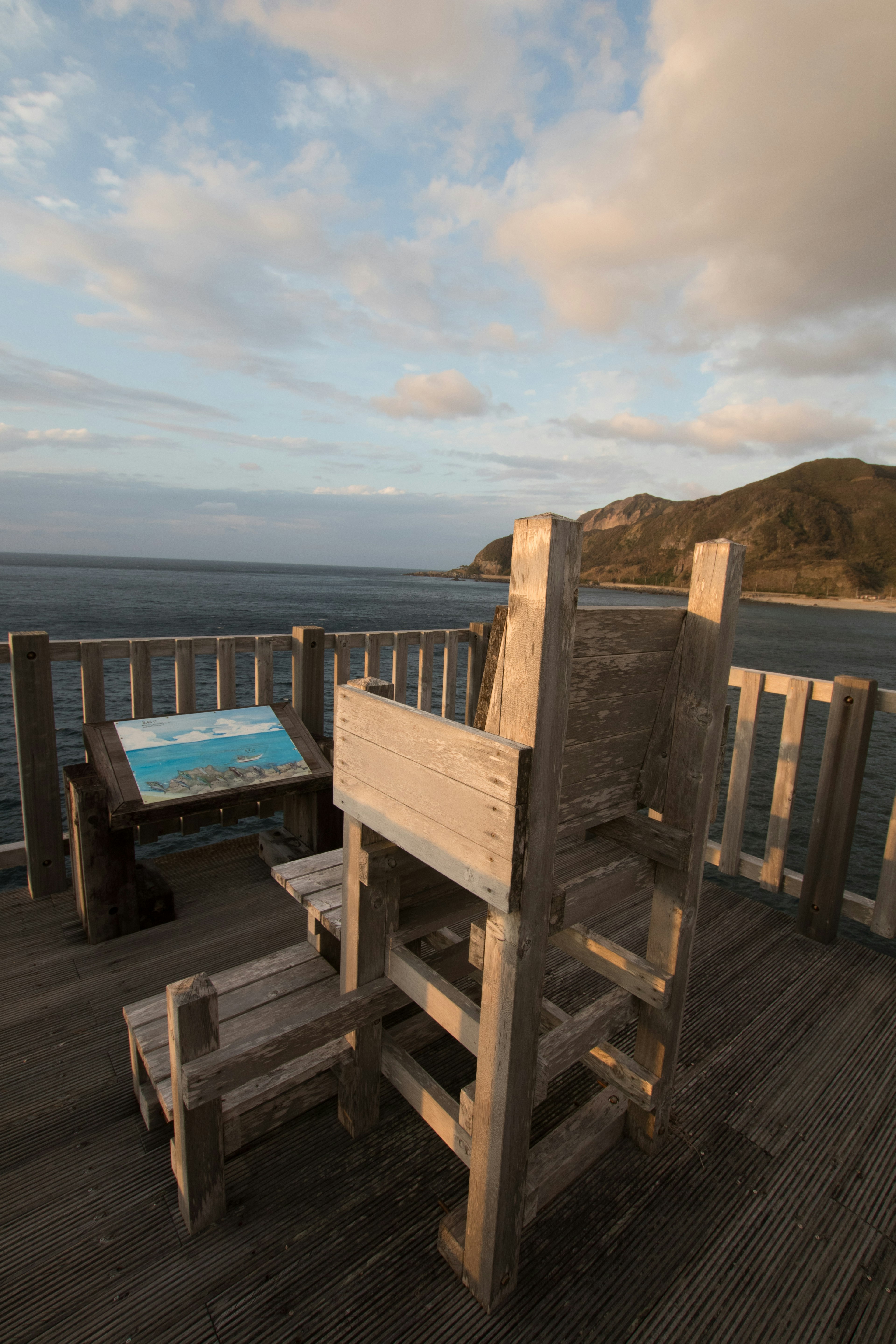 Ein Holzstuhl und ein Tisch mit Blick auf das Meer von einer Aussichtsplattform