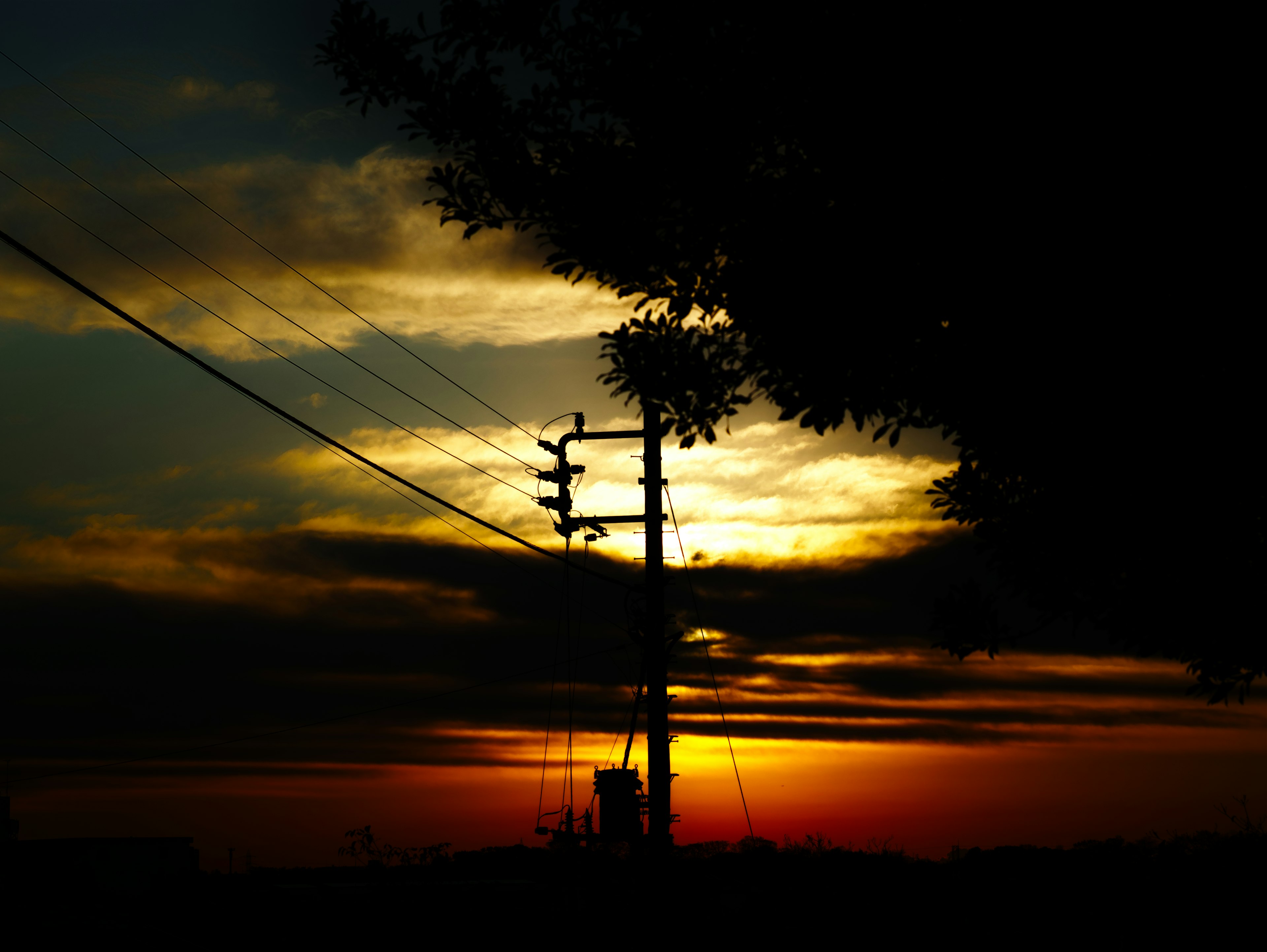 Silhouette of a power pole against a sunset sky