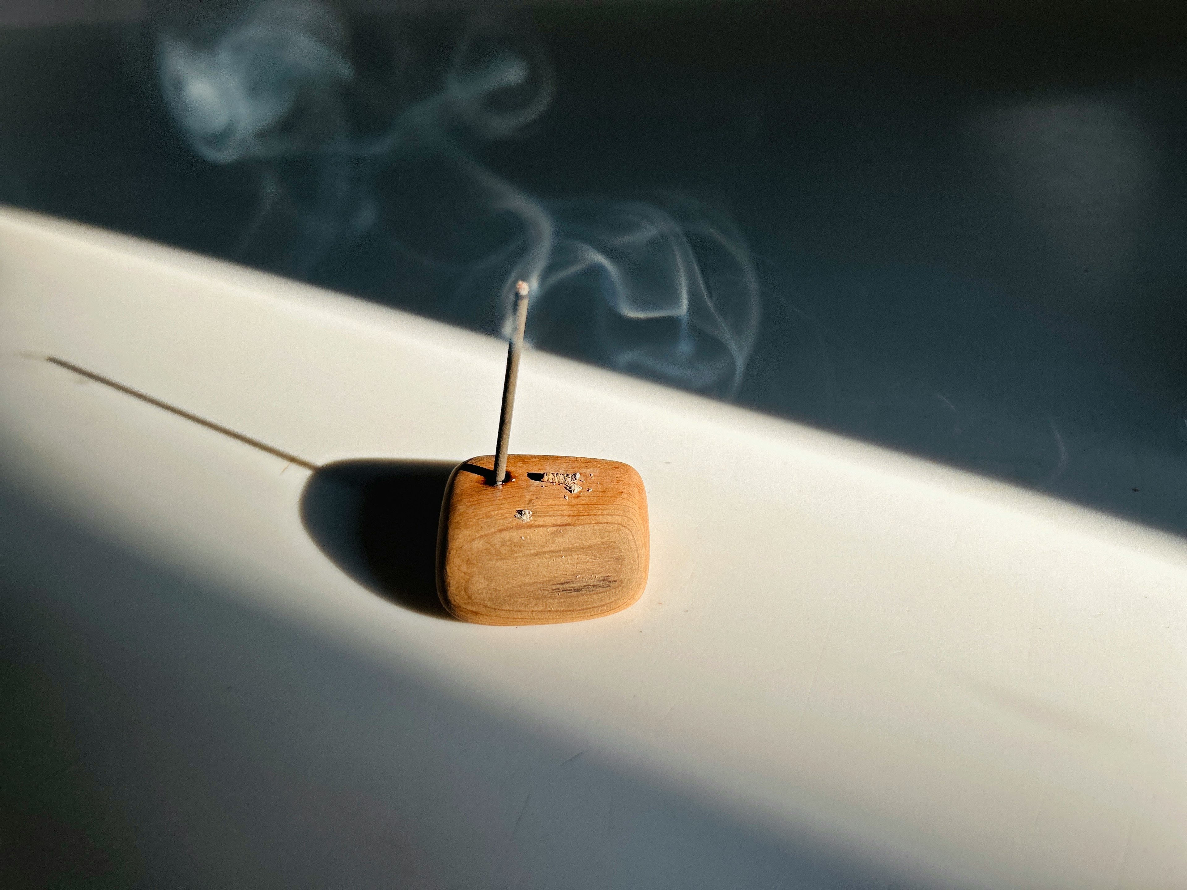 A simple scene of smoke rising from a wooden incense holder