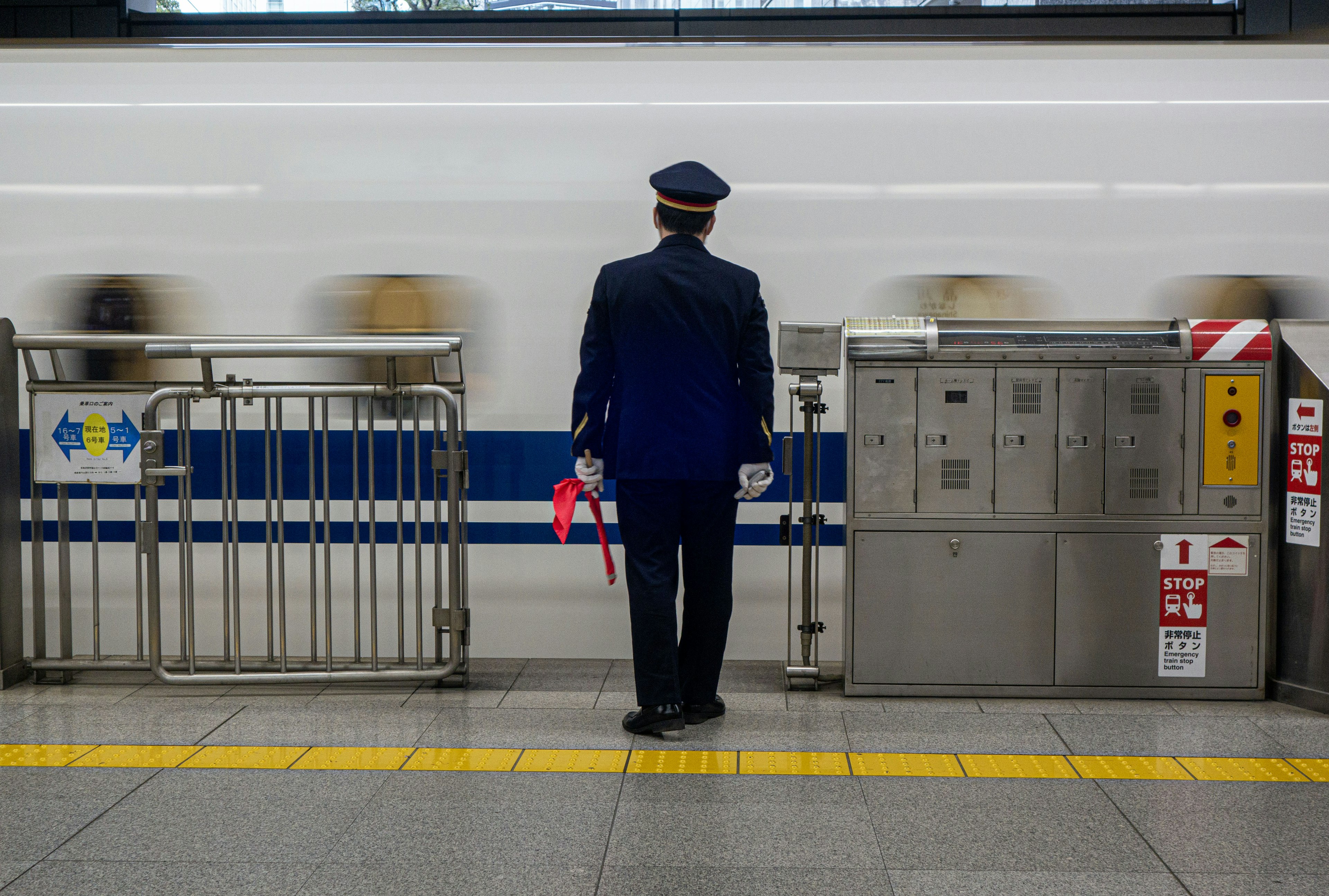 เจ้าหน้าที่รักษาความปลอดภัยยืนอยู่ที่สถานีรถไฟมองรถไฟที่กำลังวิ่งผ่าน