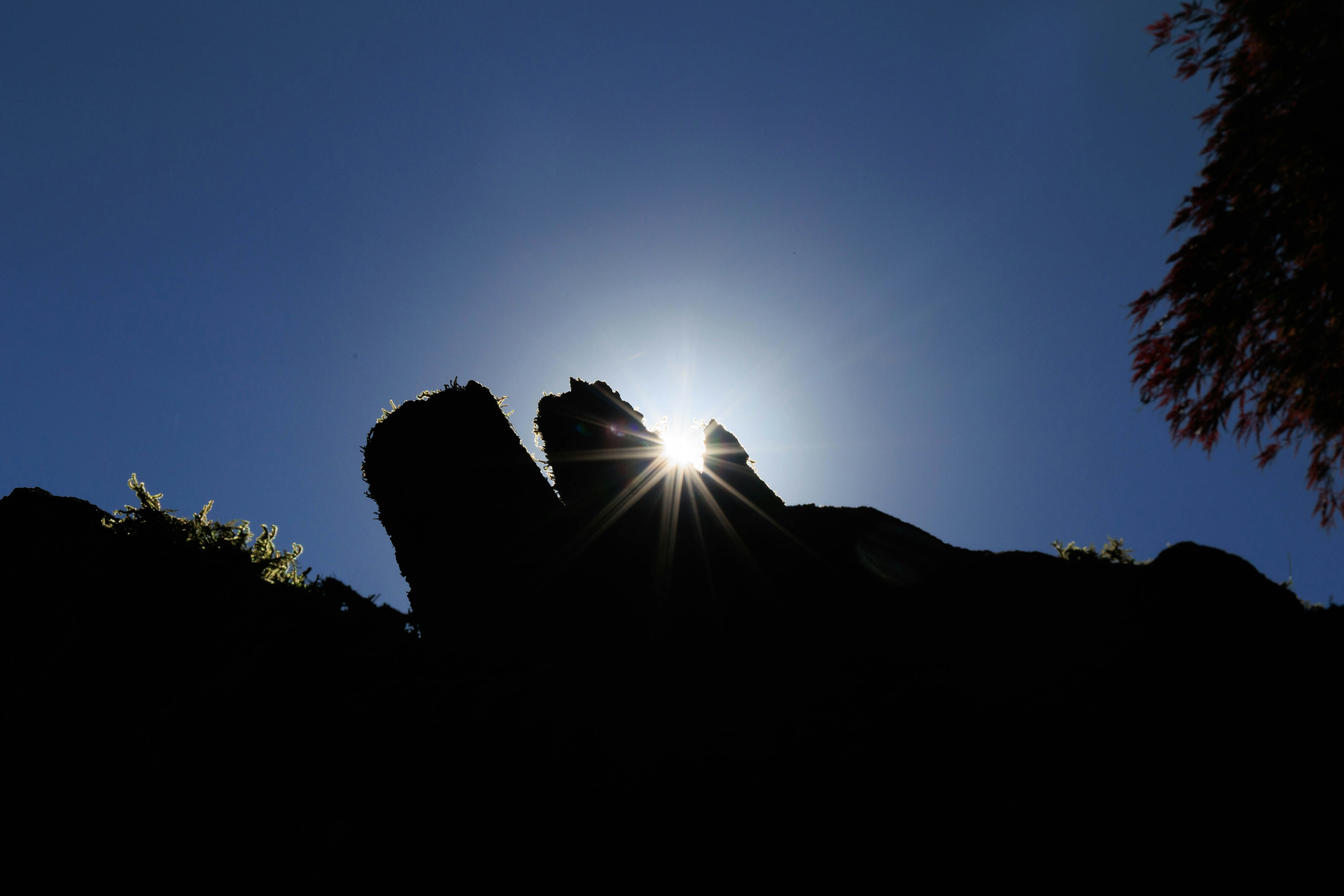 Silueta de rocas contra un cielo brillante con luz solar