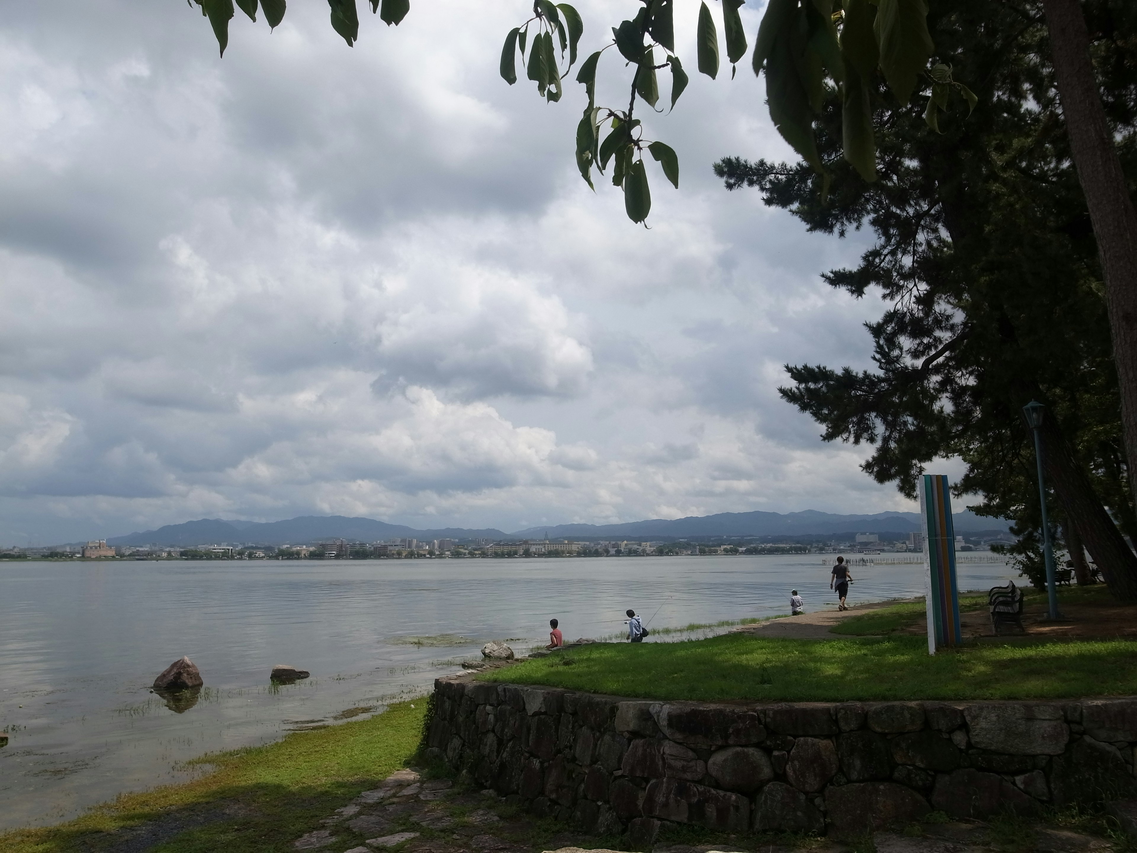 Vista del lago con cielo nublado y personas presentes