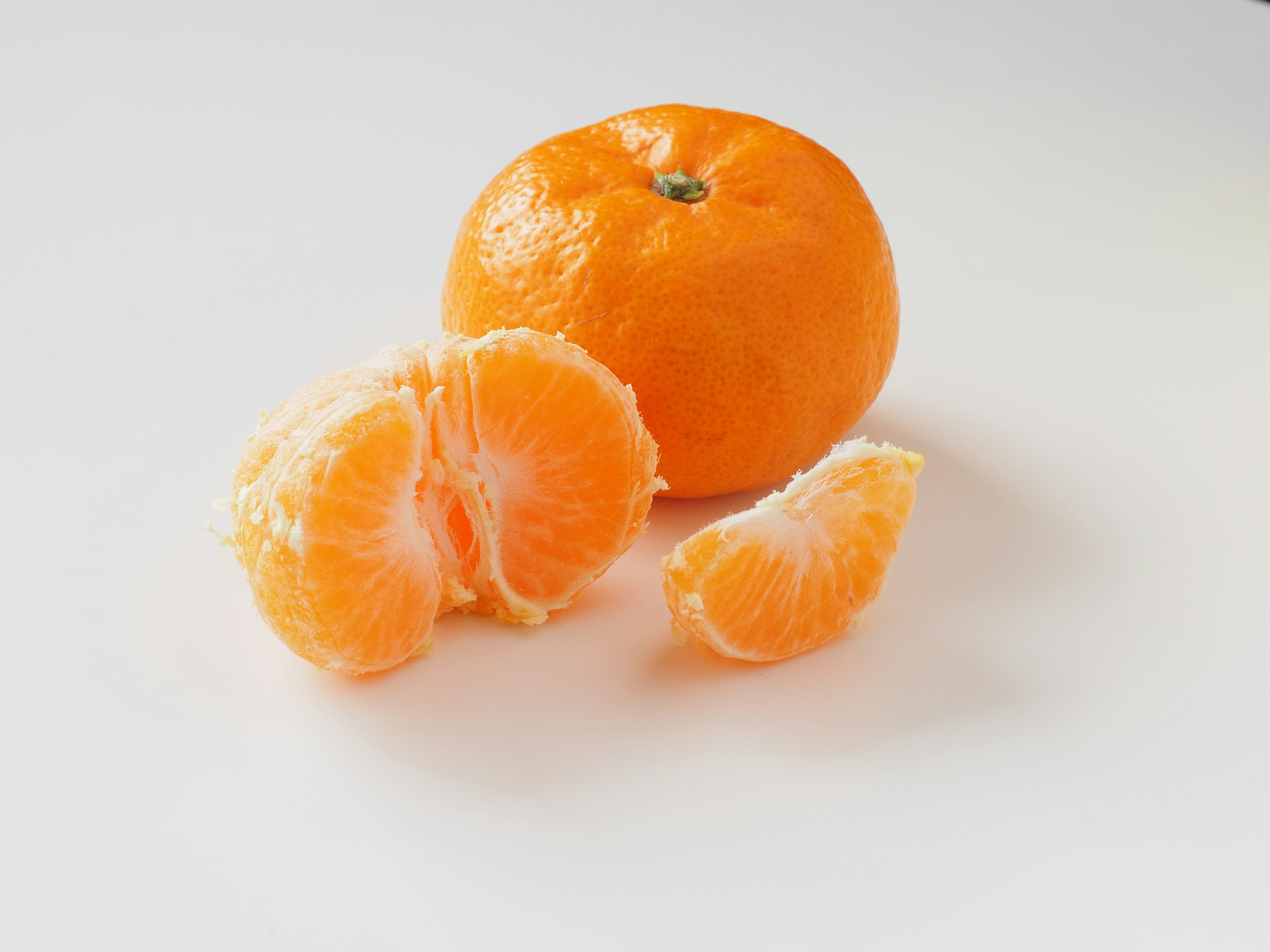 Eine ganze Orange mit teilweise getrennten Segmenten auf einem weißen Hintergrund