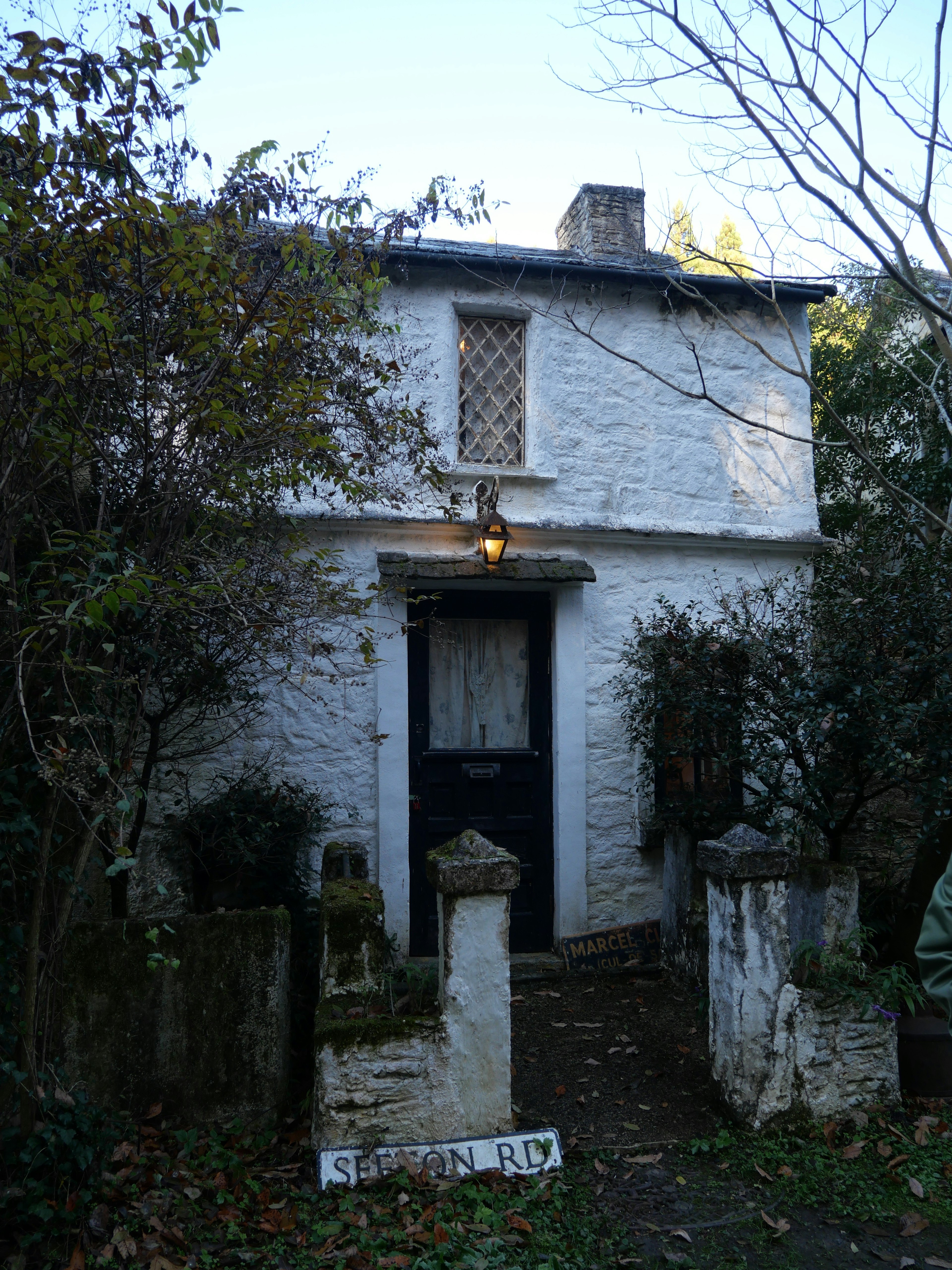 Old white house exterior surrounded by plants entrance with lattice window design