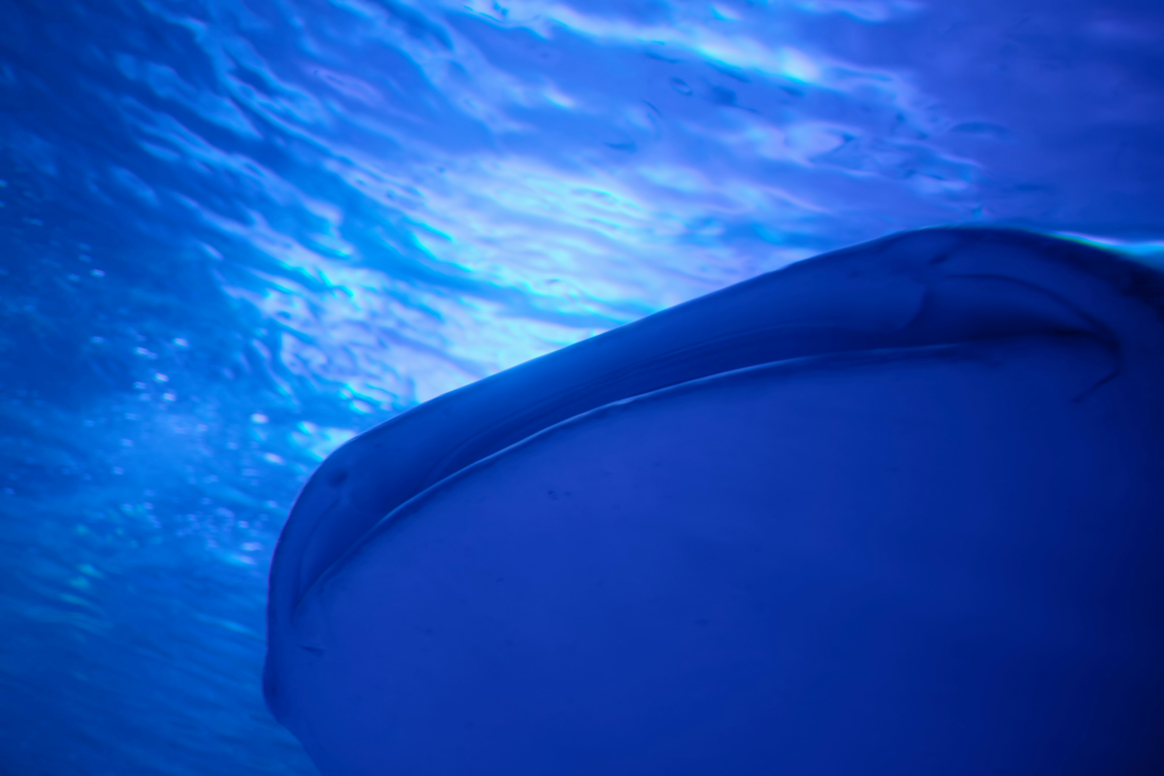 Underwater view of blue waves and smooth boat hull