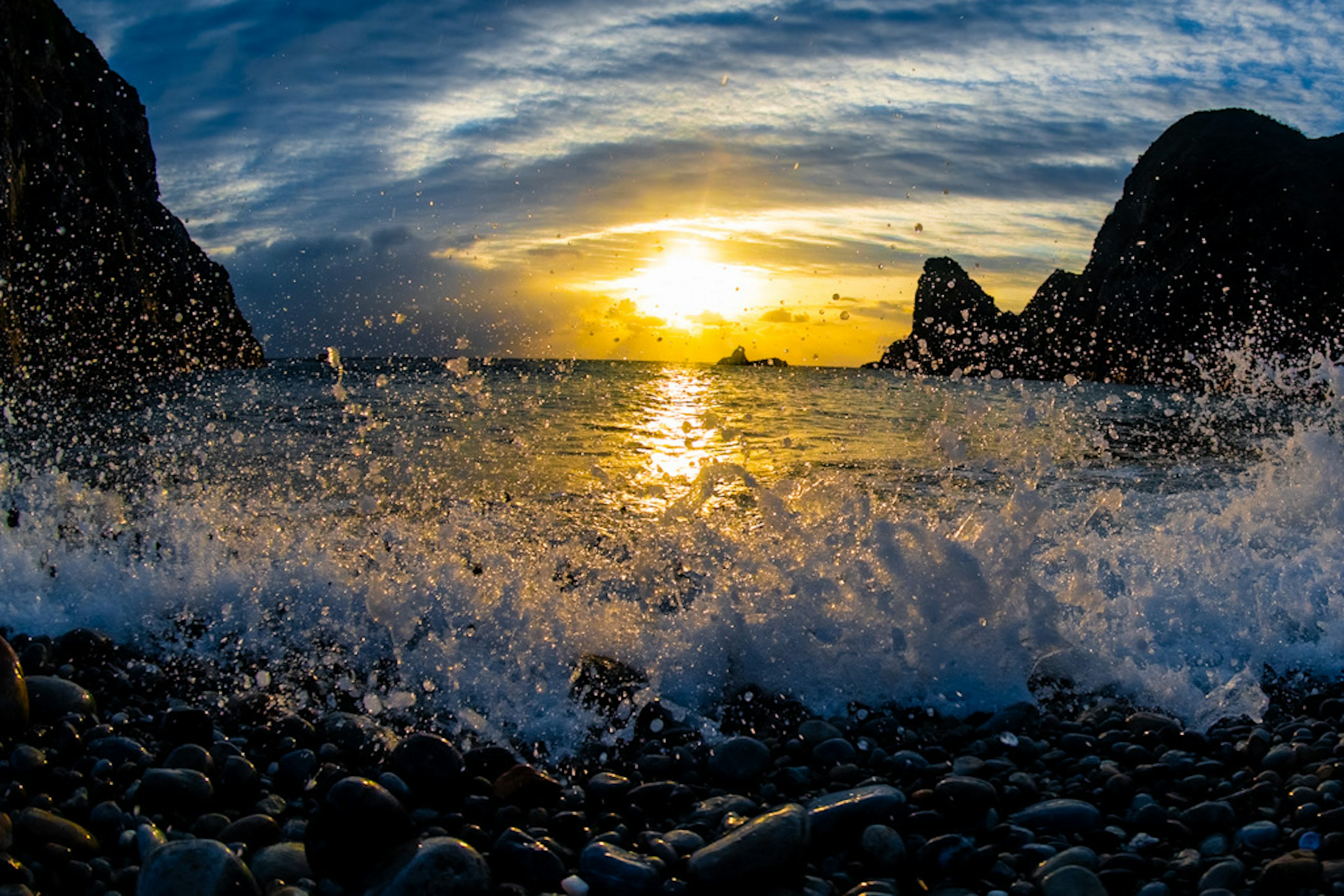 海浪在日落時衝擊岩石海灘