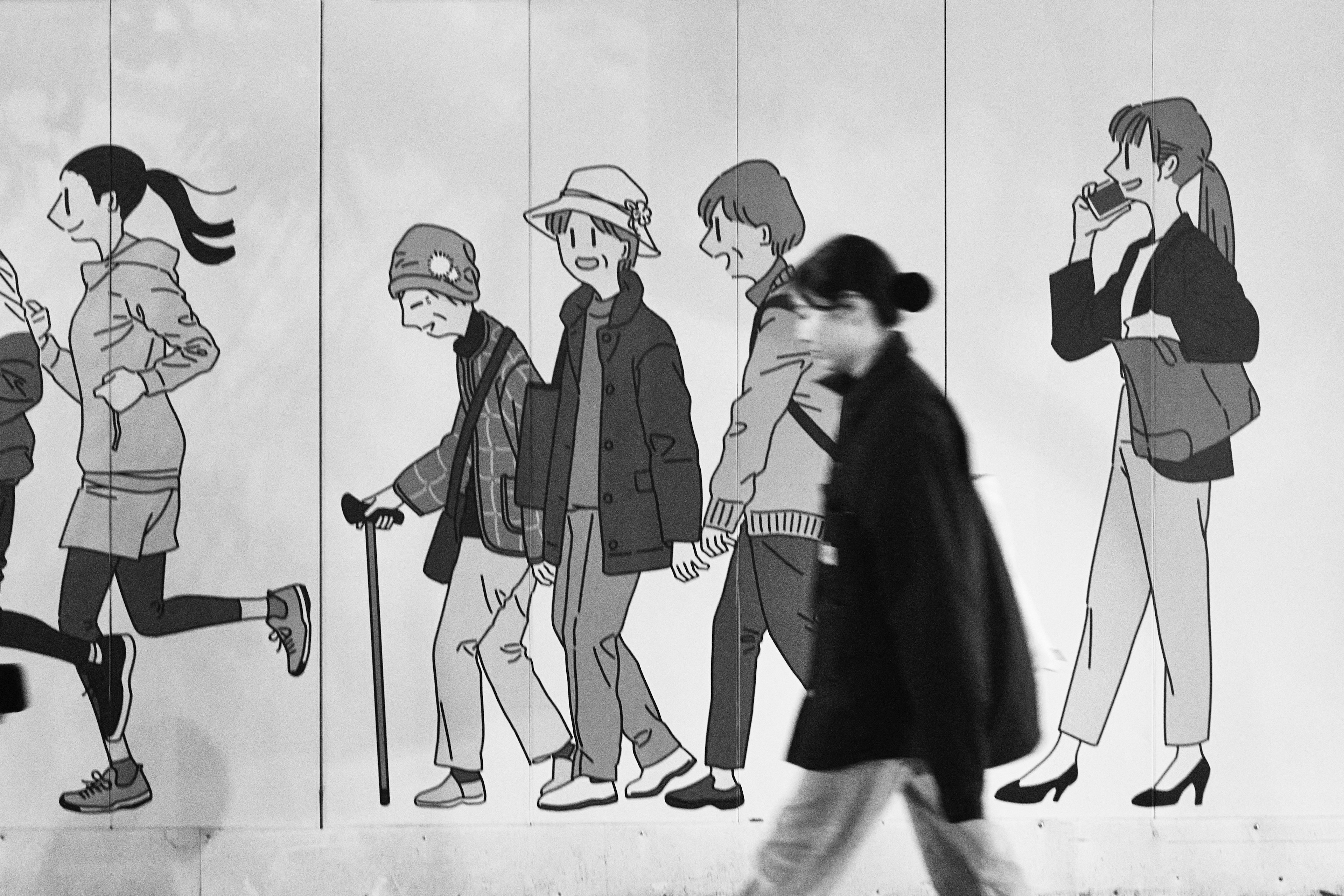 Un mural en blanco y negro que muestra a varias personas caminando junto a una persona que pasa