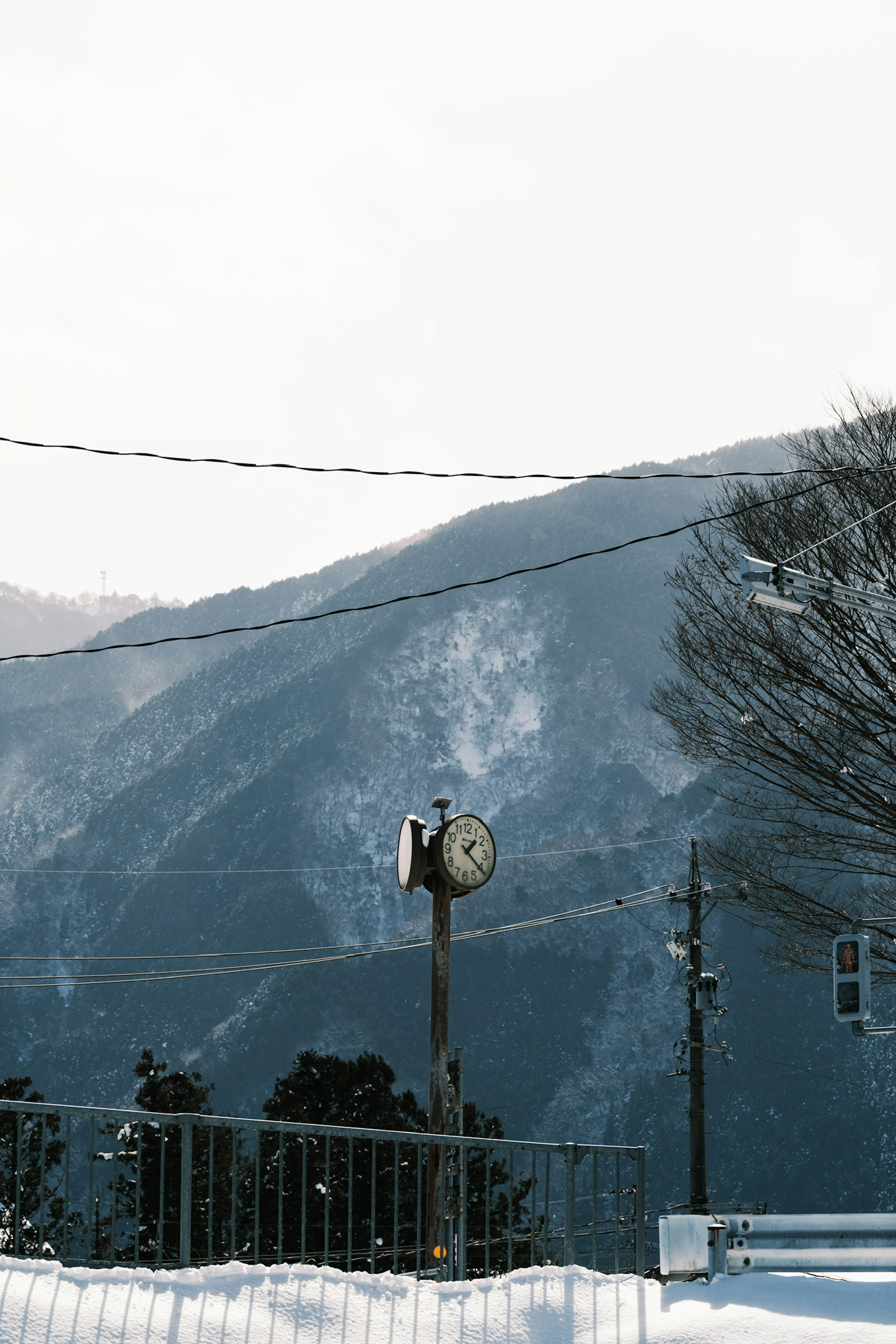 An old clock amidst a snowy landscape with mountains in the background