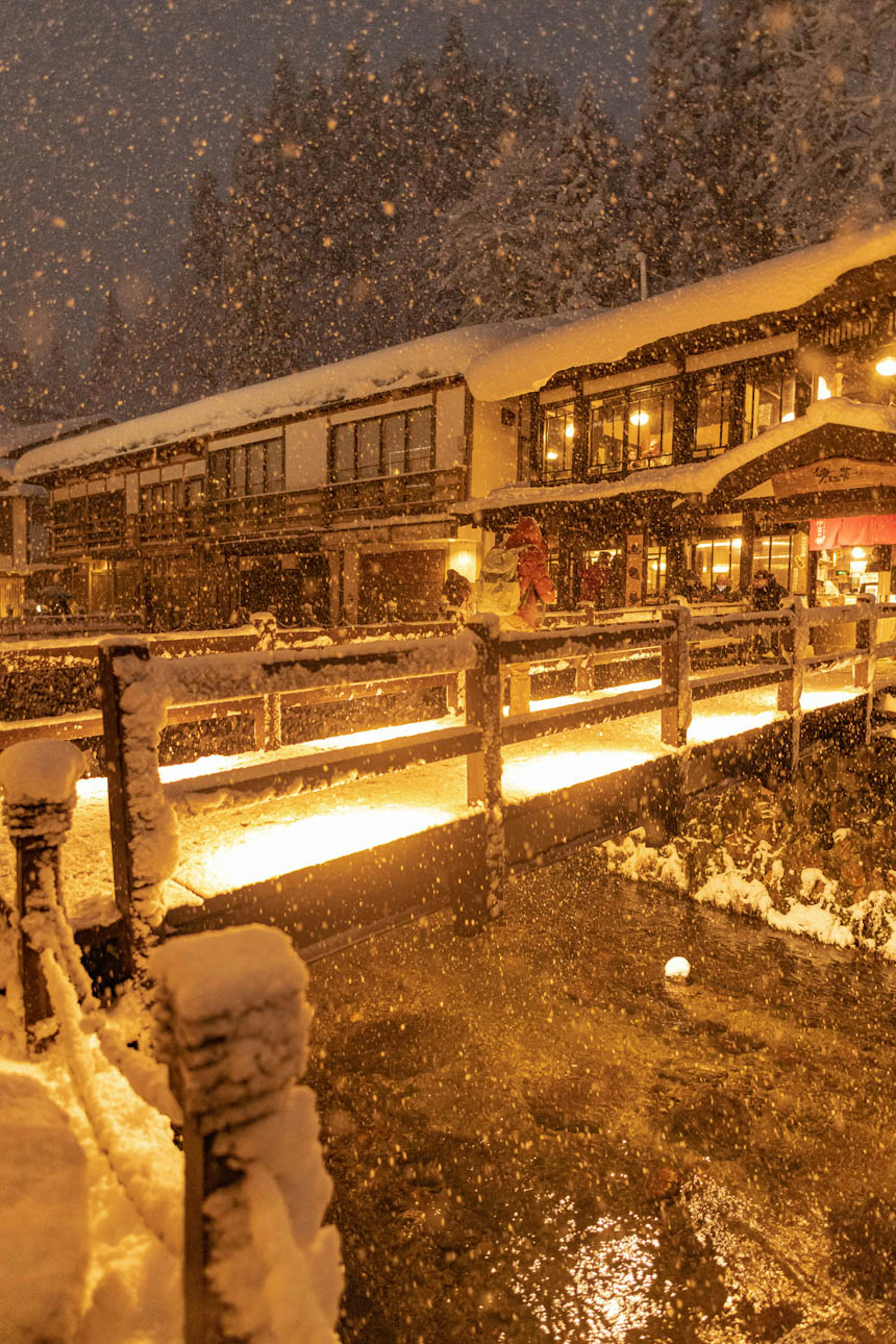 雪の中の橋と温かい光を放つ建物の風景