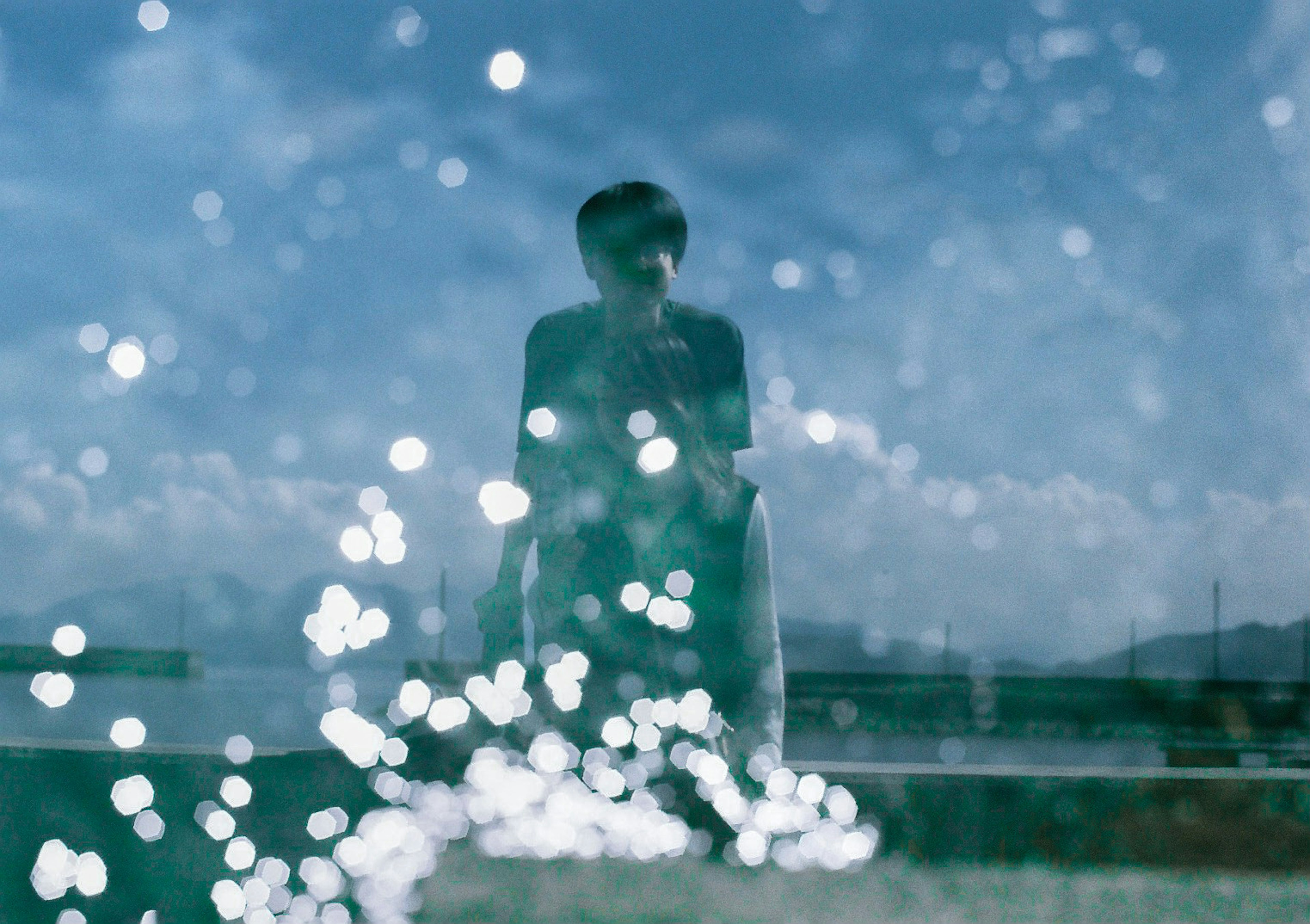 Person standing in front of splashing water with blue sky and clouds