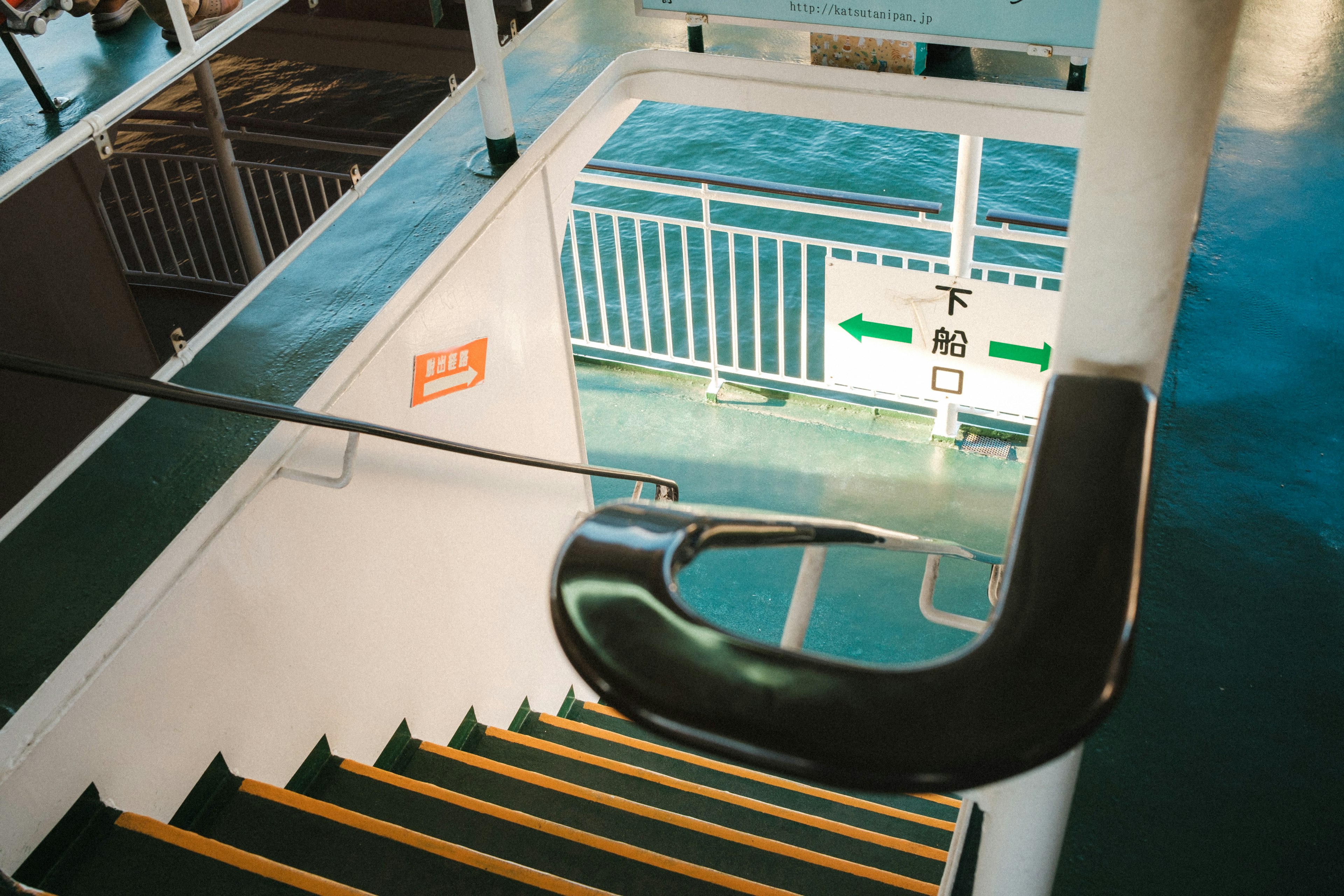 Vista interior de una escalera de ferry con pasamanos y mar azul visible