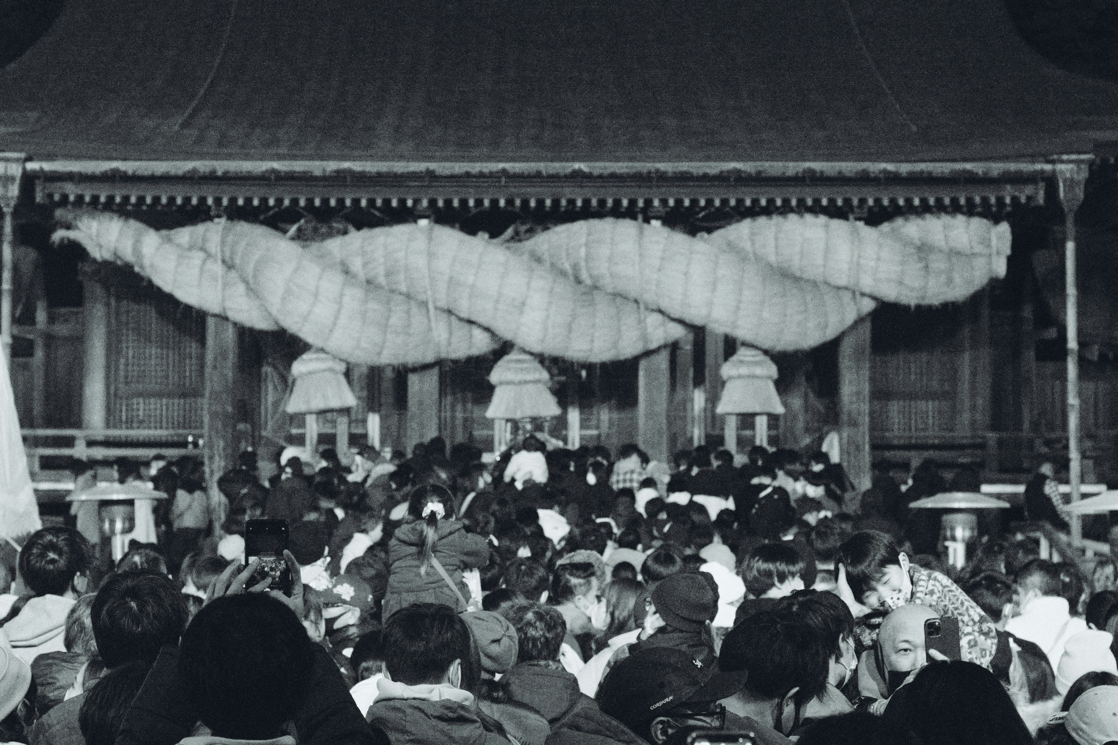 Crowd gathered at a traditional festival with decorated building in the background