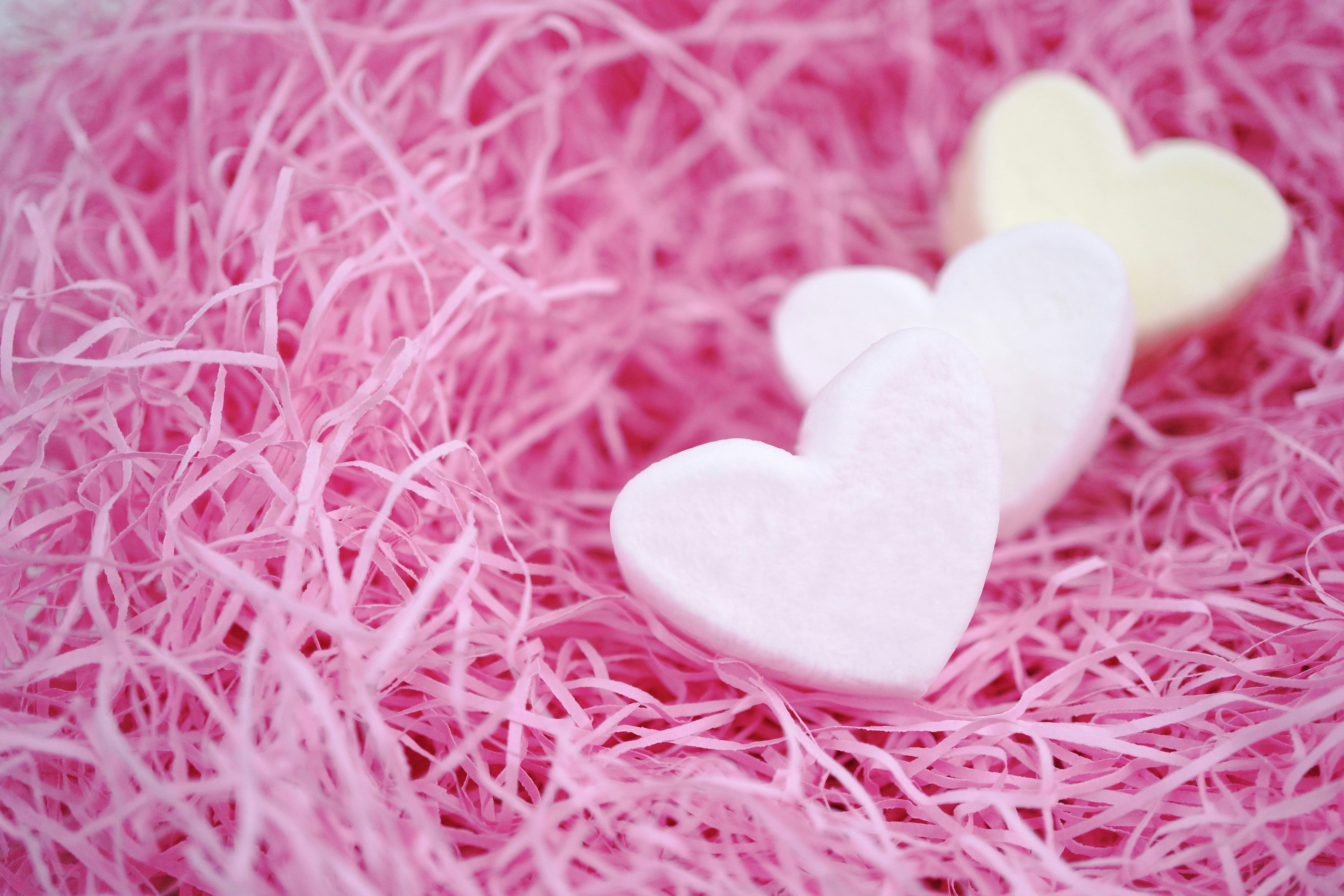 Dulces en forma de corazón sobre material rosa similar a paja