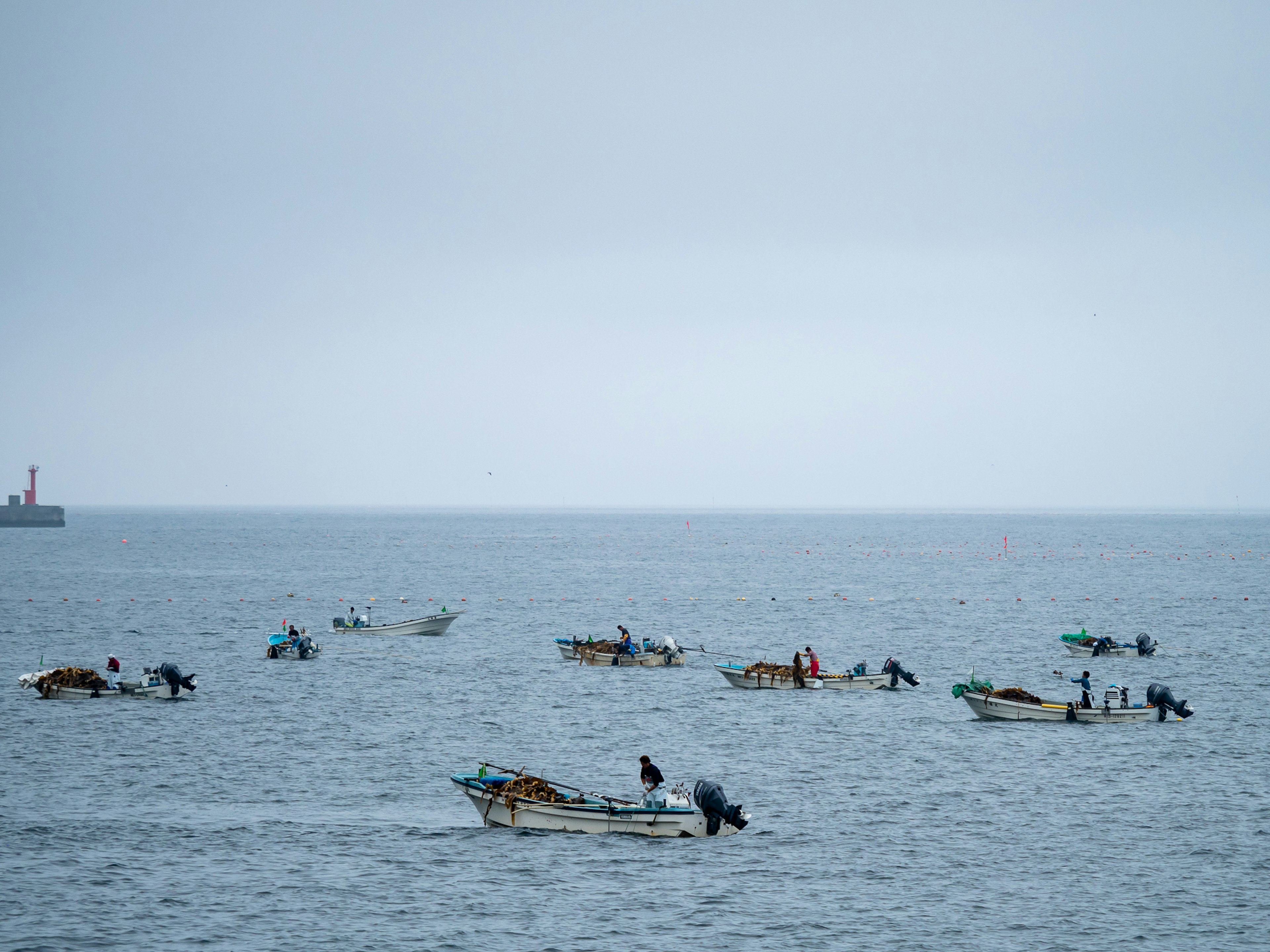 Una escena con numerosos pequeños barcos de pesca en el océano