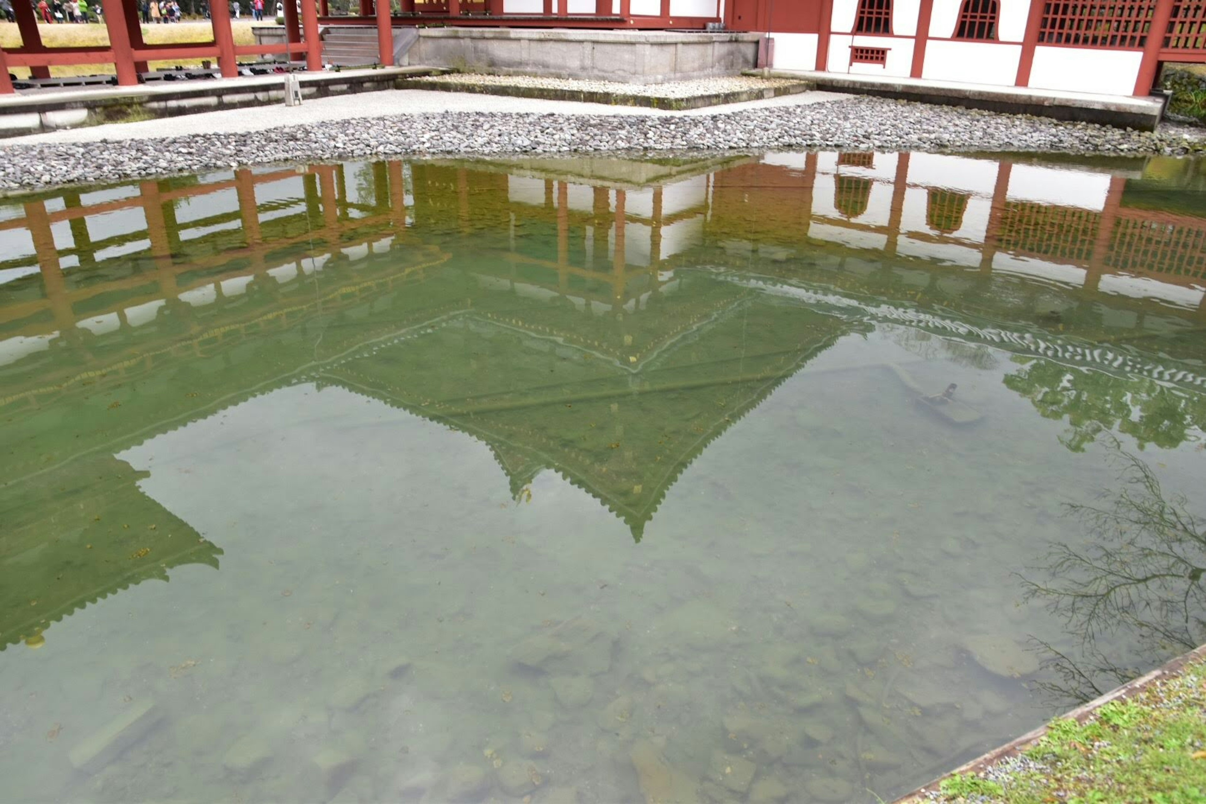 Reflection of a traditional building in water with surrounding landscape