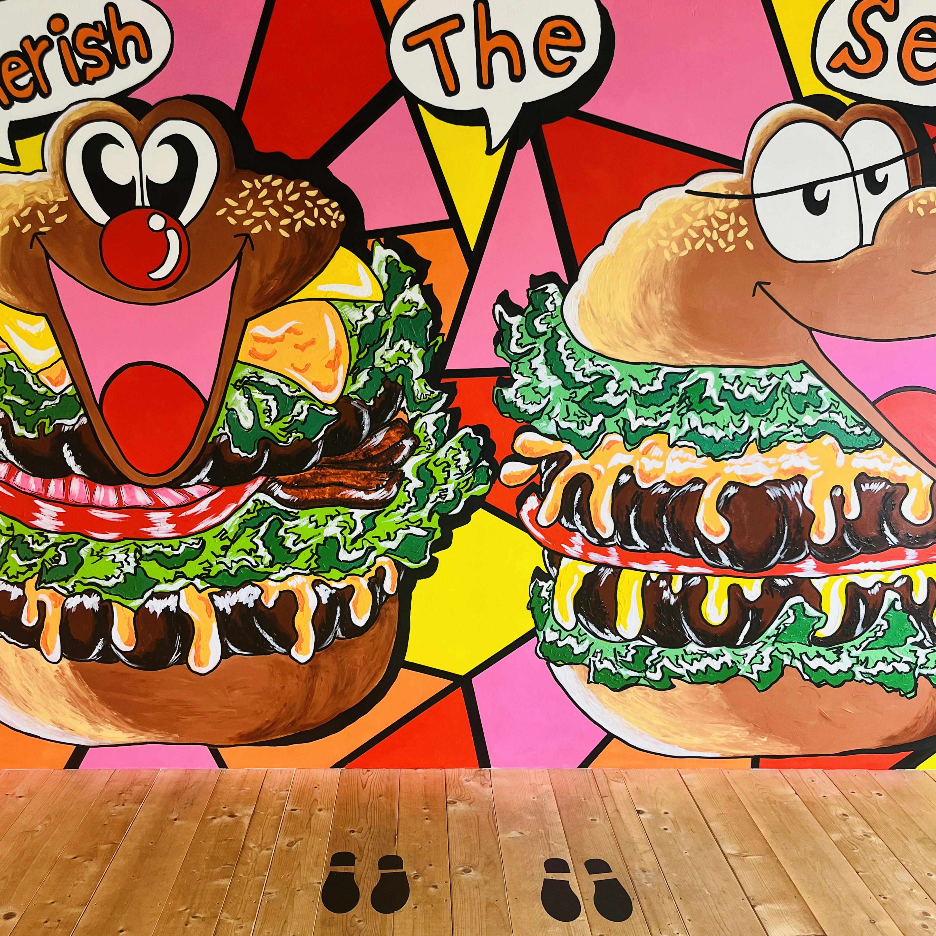 Mural coloré avec deux personnages de hamburger souriants et des expressions ludiques