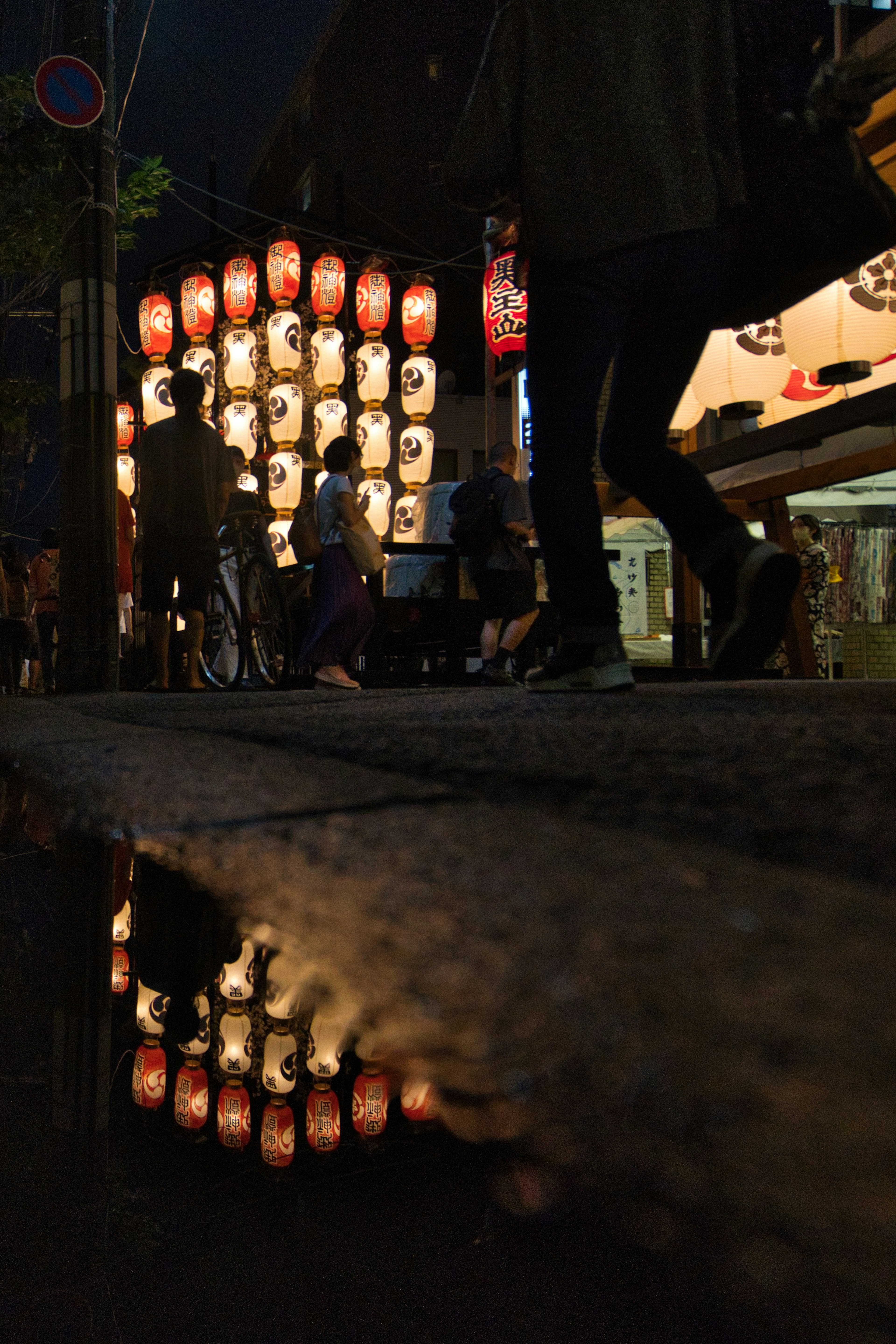 Reflejos de linternas en la calle nocturna y pasos de personas