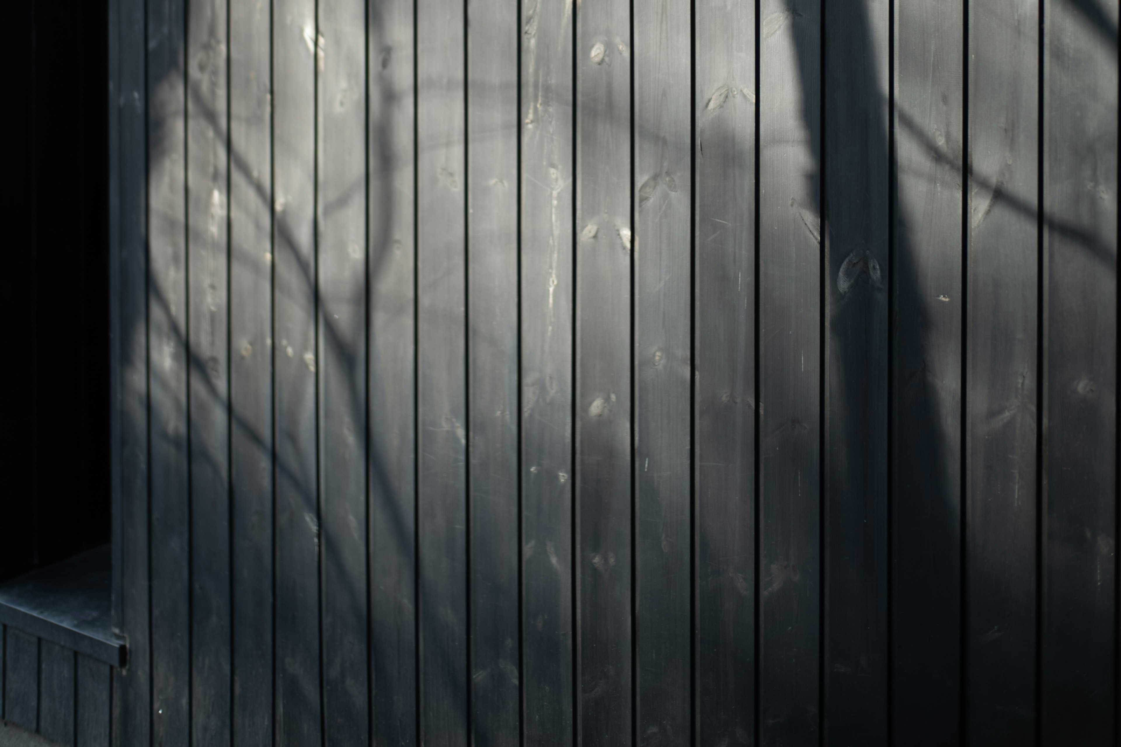 Pared de madera oscura con sombras y contraste de luz