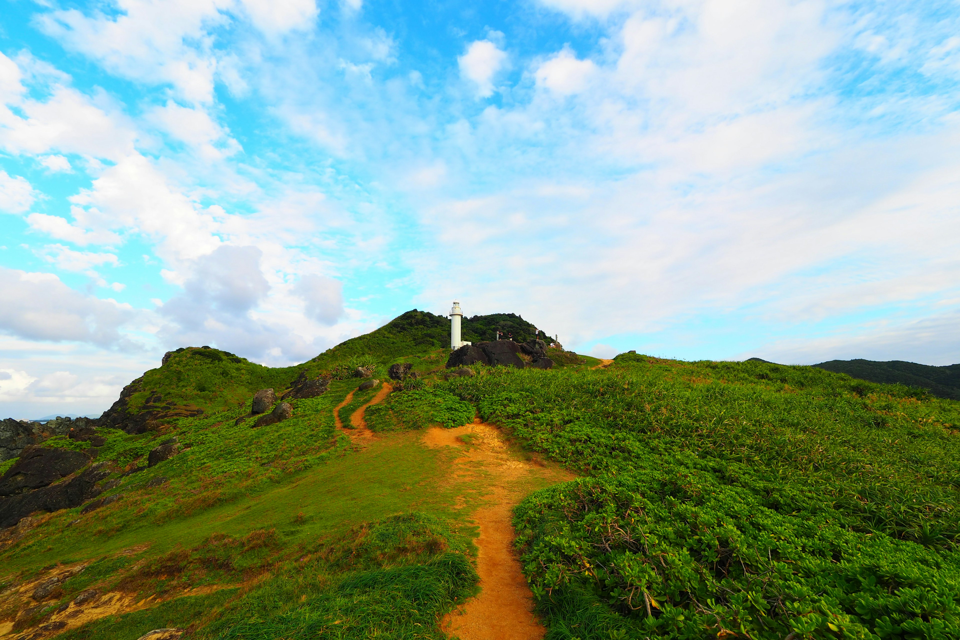 Phare sur une colline verte sous un ciel bleu