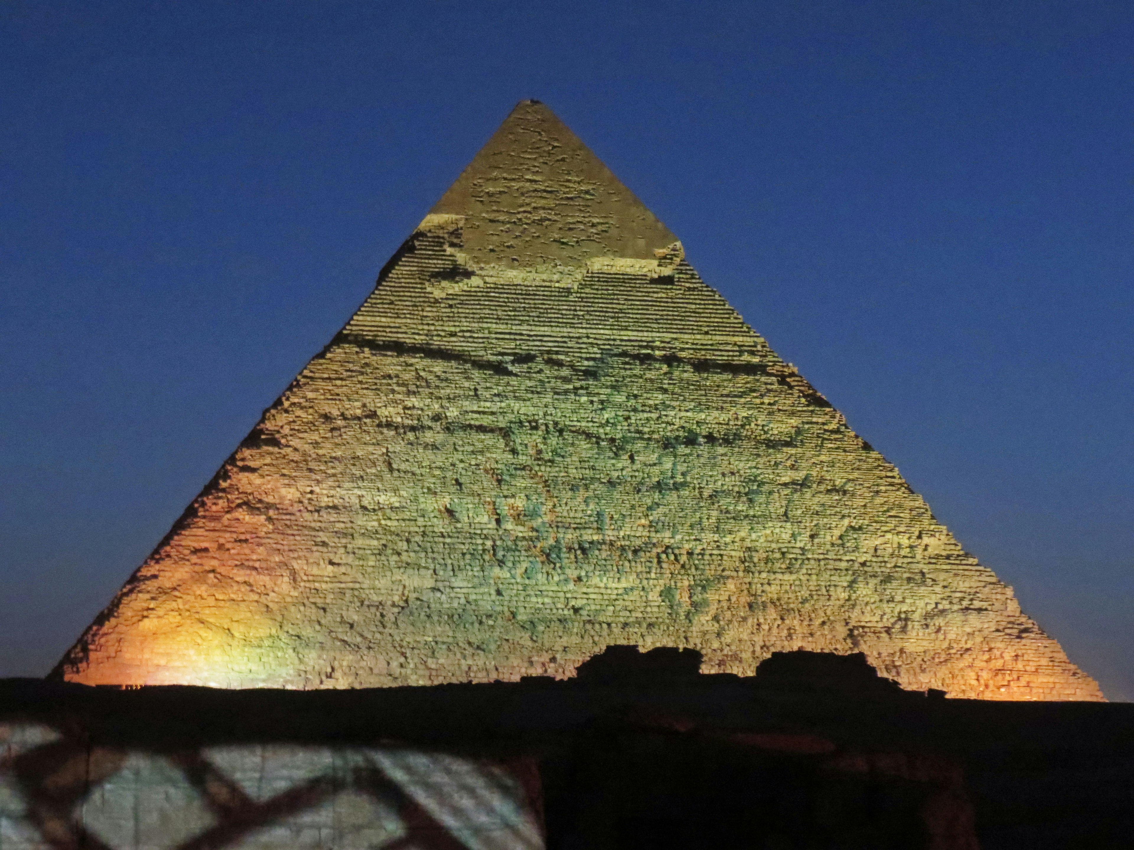 Iluminación vibrante y sombras en una pirámide bajo el cielo nocturno