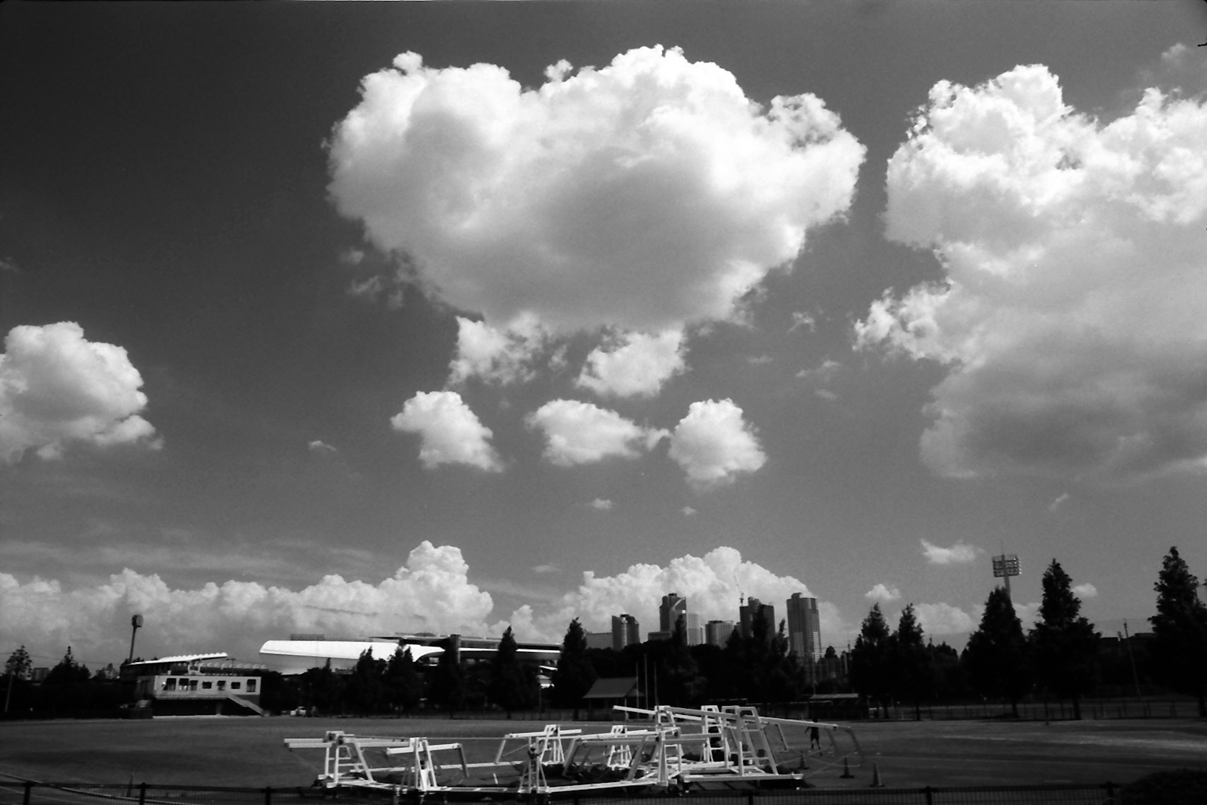 Black and white landscape featuring large clouds and silhouetted buildings