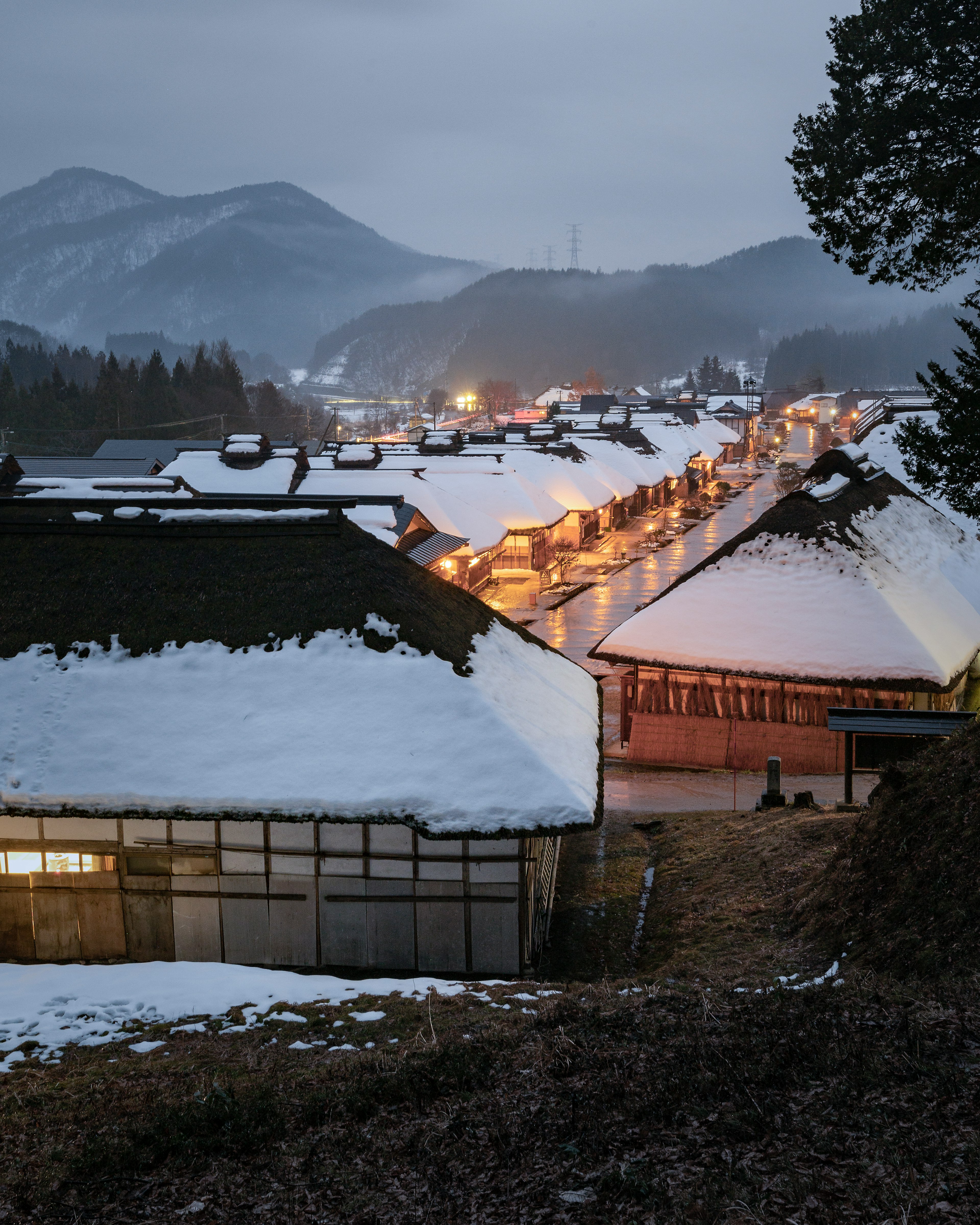 Traditionelle Häuser bedeckt mit Schnee vor einer ruhigen Berglandschaft