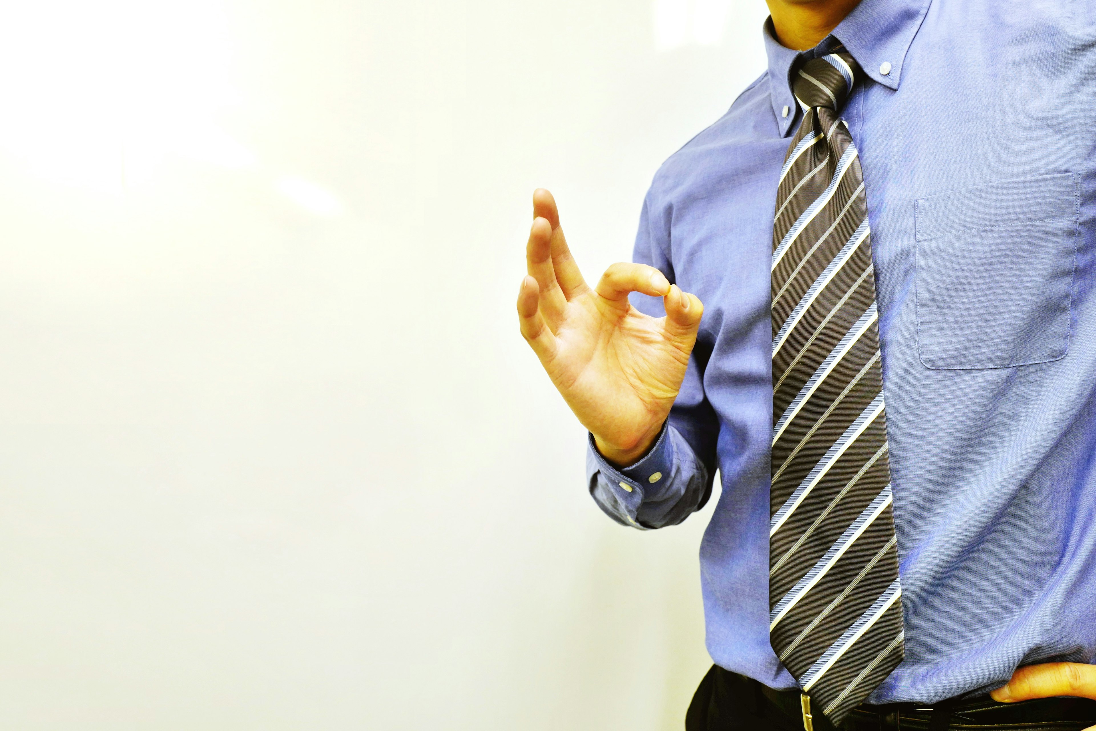 Un hombre con camisa azul haciendo un gesto de OK con la mano