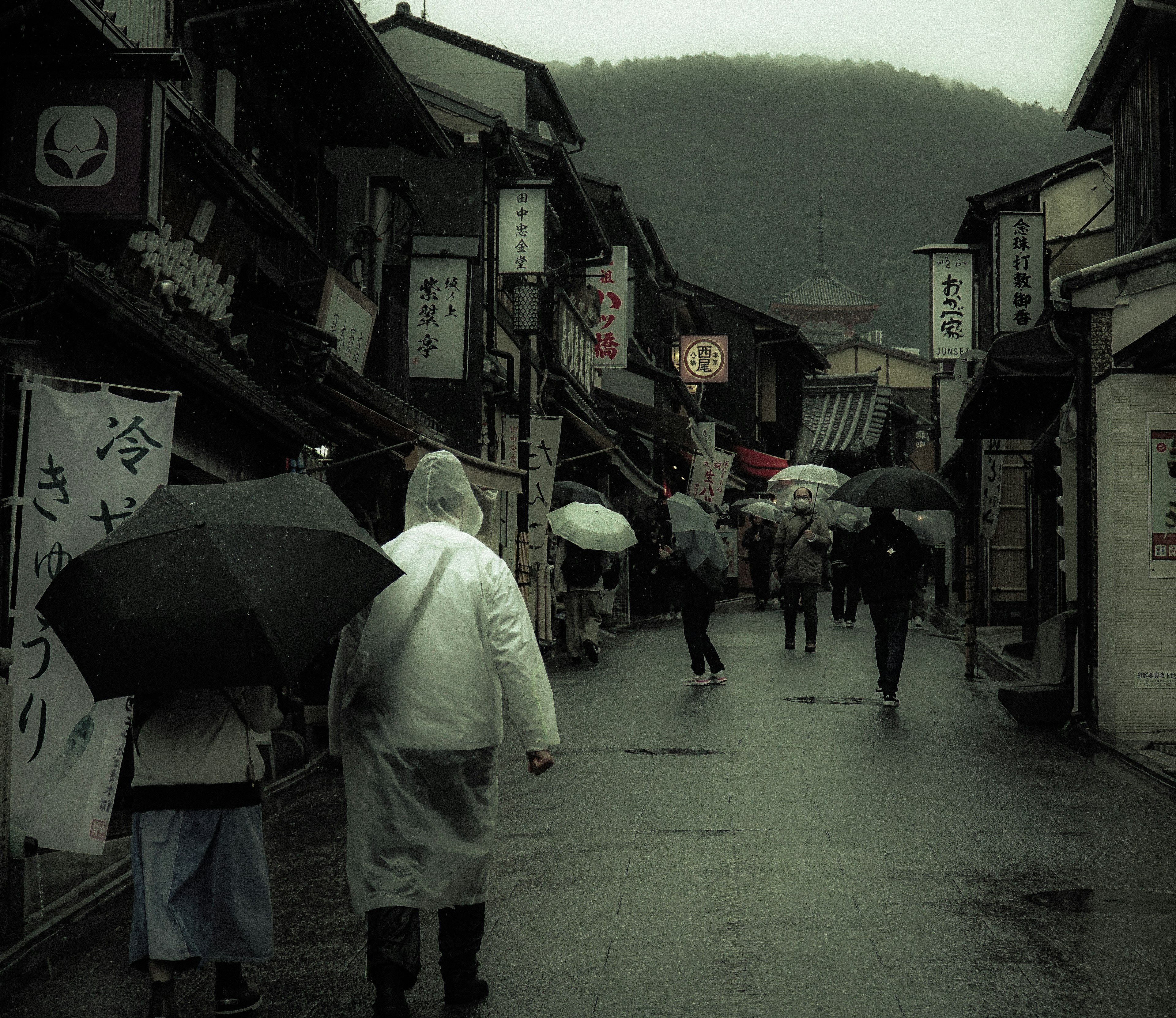 人们在雨中走过，街道两旁是传统建筑