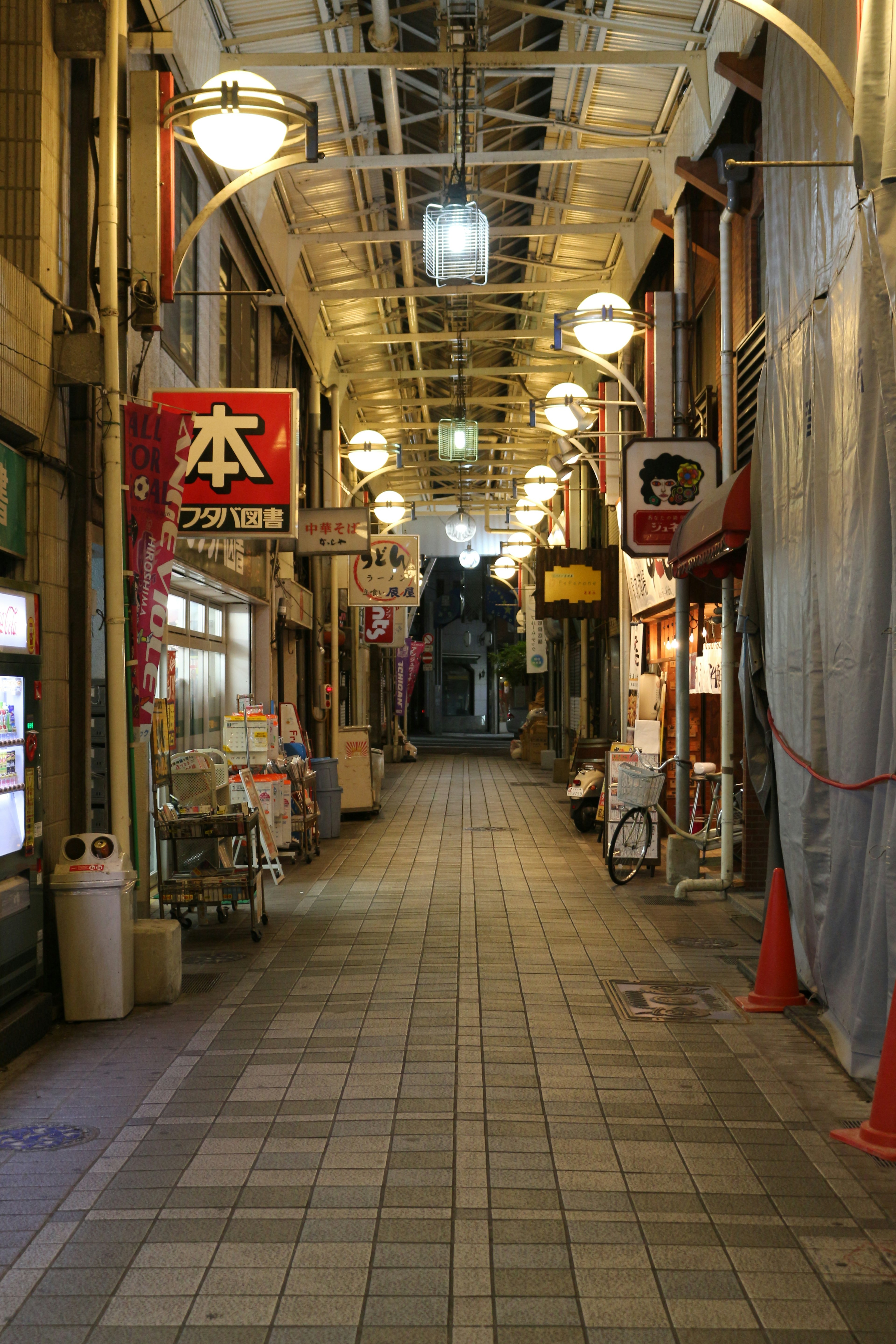 狭いアーケードの通りに並ぶ店舗と明るい照明