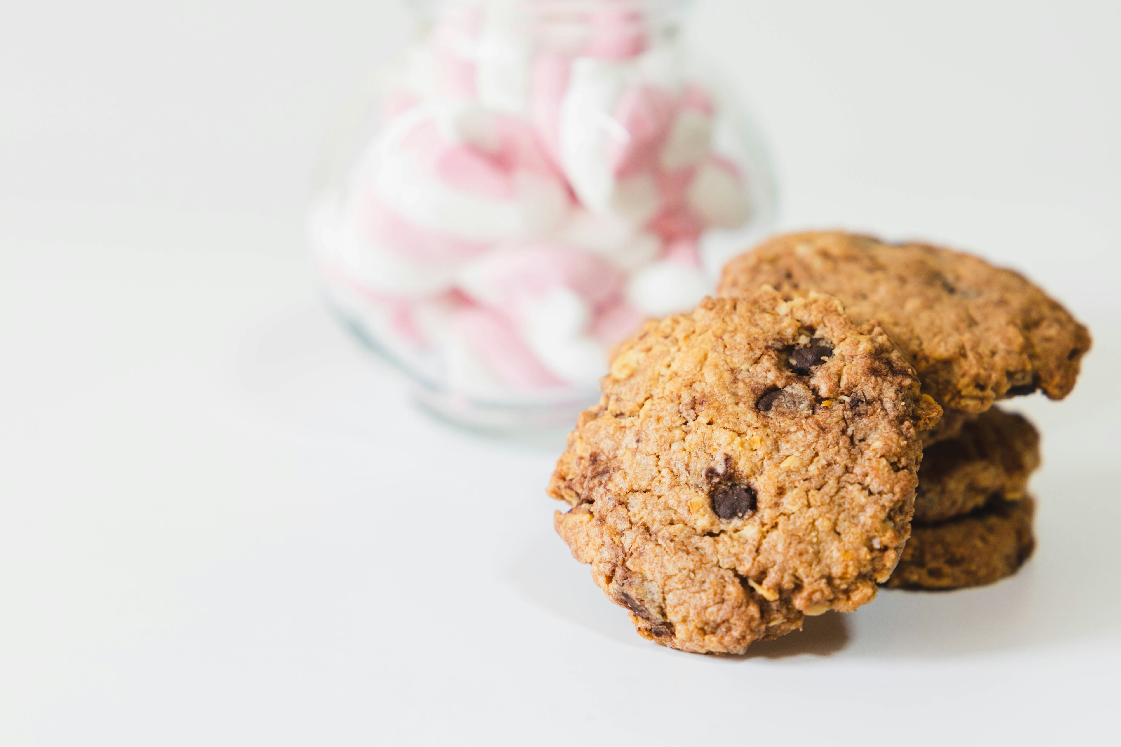 Imagen de galletas con un frasco de malvaviscos en un fondo simple