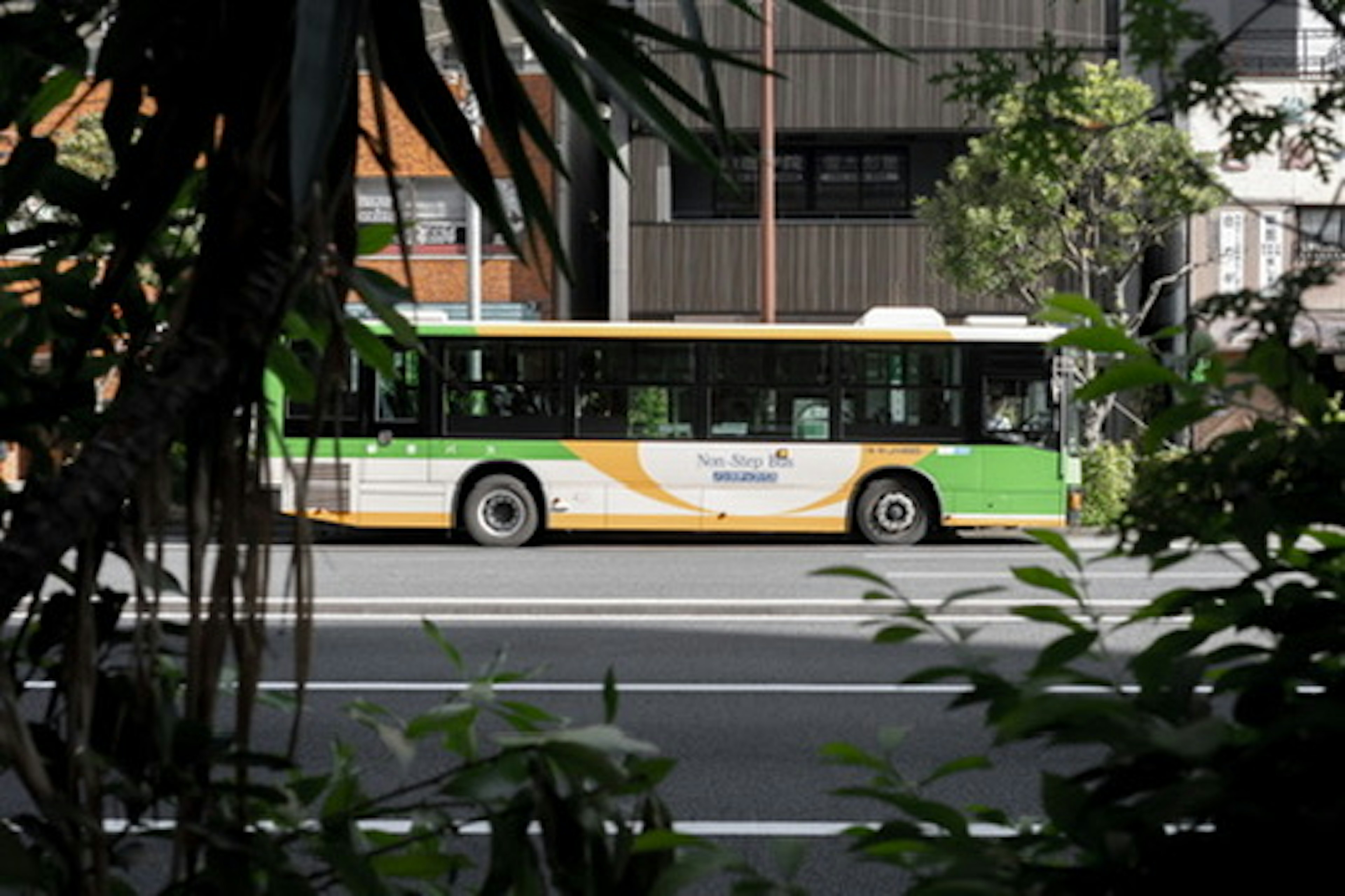 Ein grüner und orangefarbener Bus, der durch die Stadt fährt