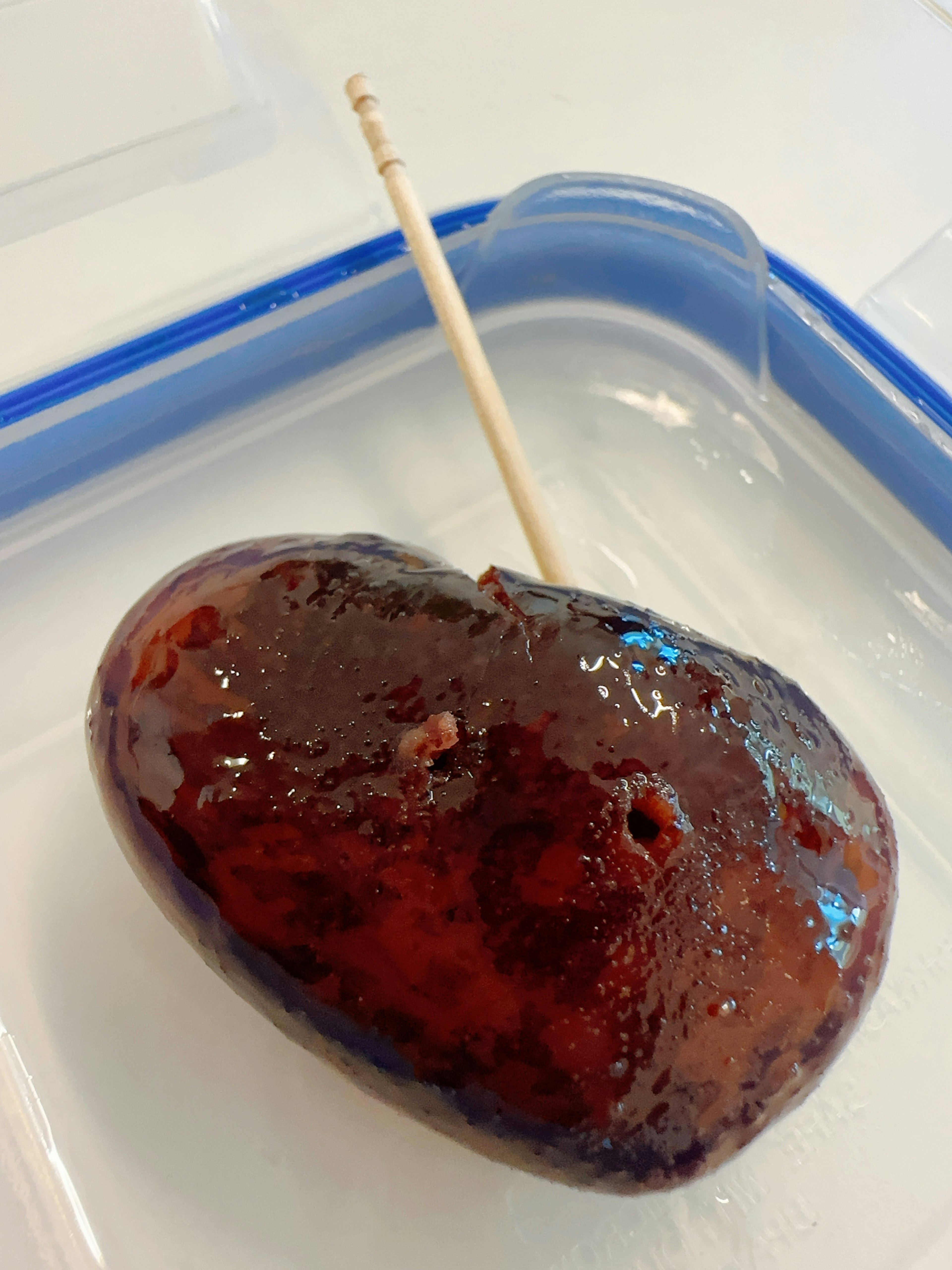 A food item resembling a red gummy candy on a stick