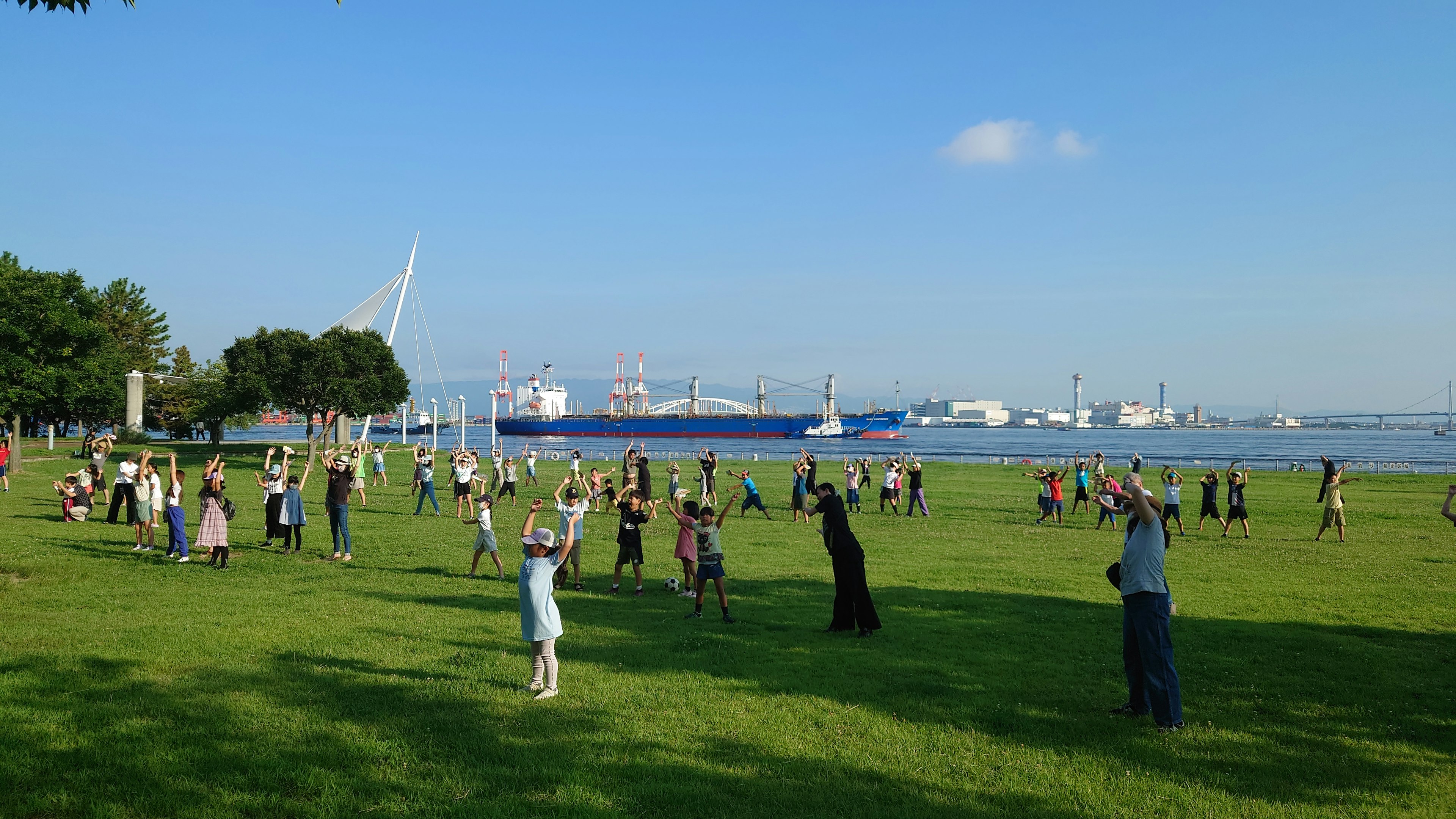 公園で集まる人々と青い海の景色