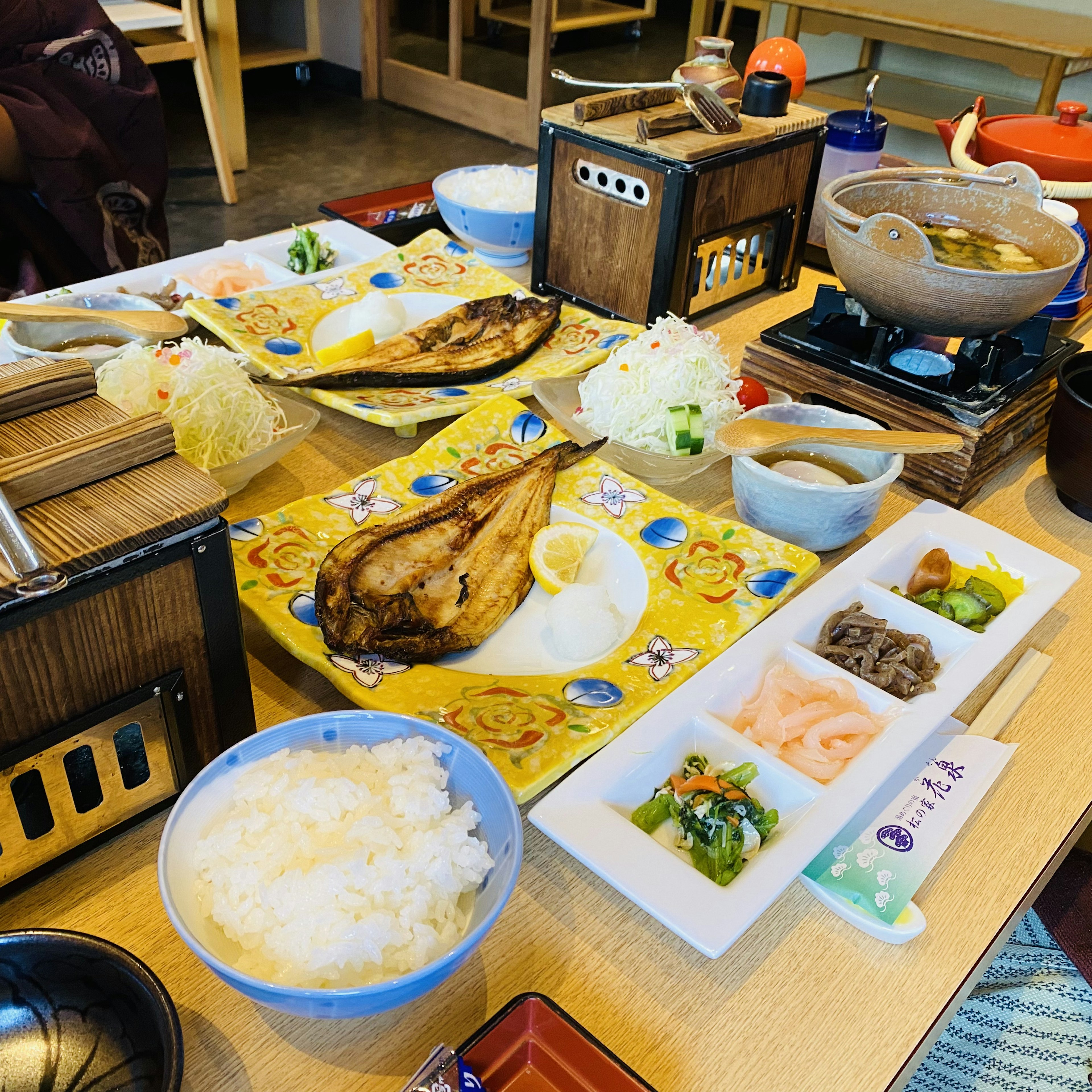 Japanese meal spread on a table featuring grilled fish rice miso soup and assorted vegetables