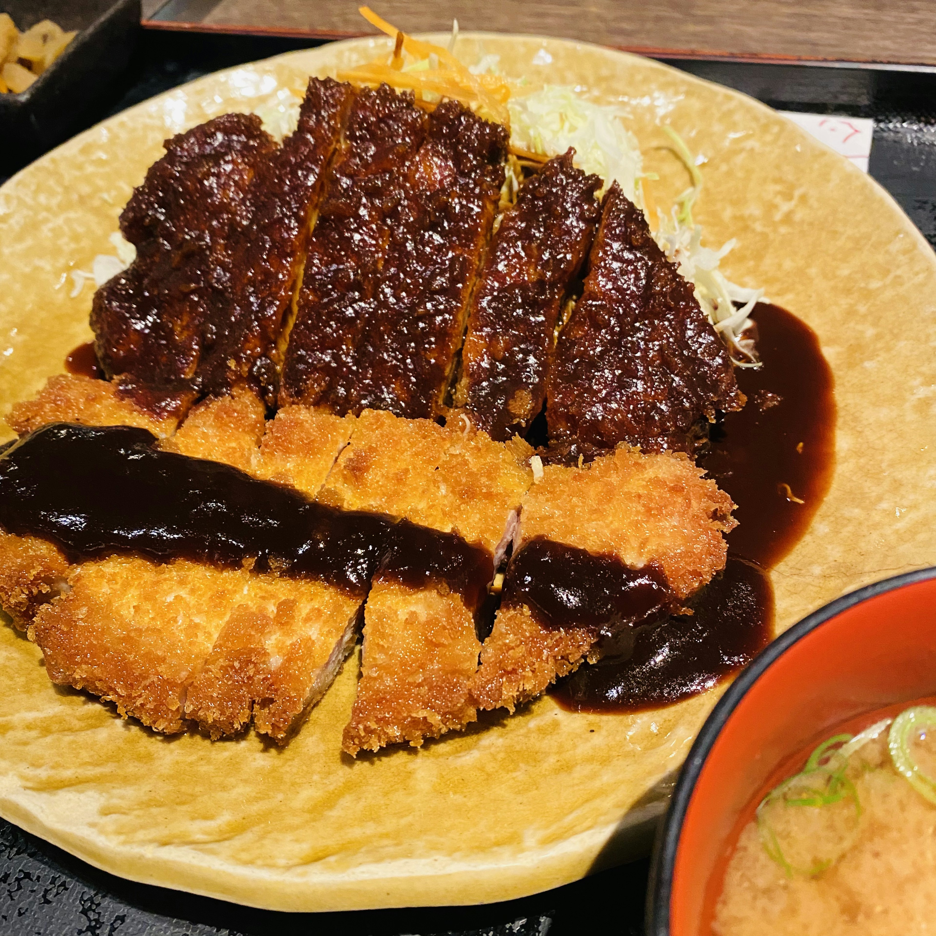 カツ丼のプレートに盛り付けられたトンカツとソースの美しい組み合わせ