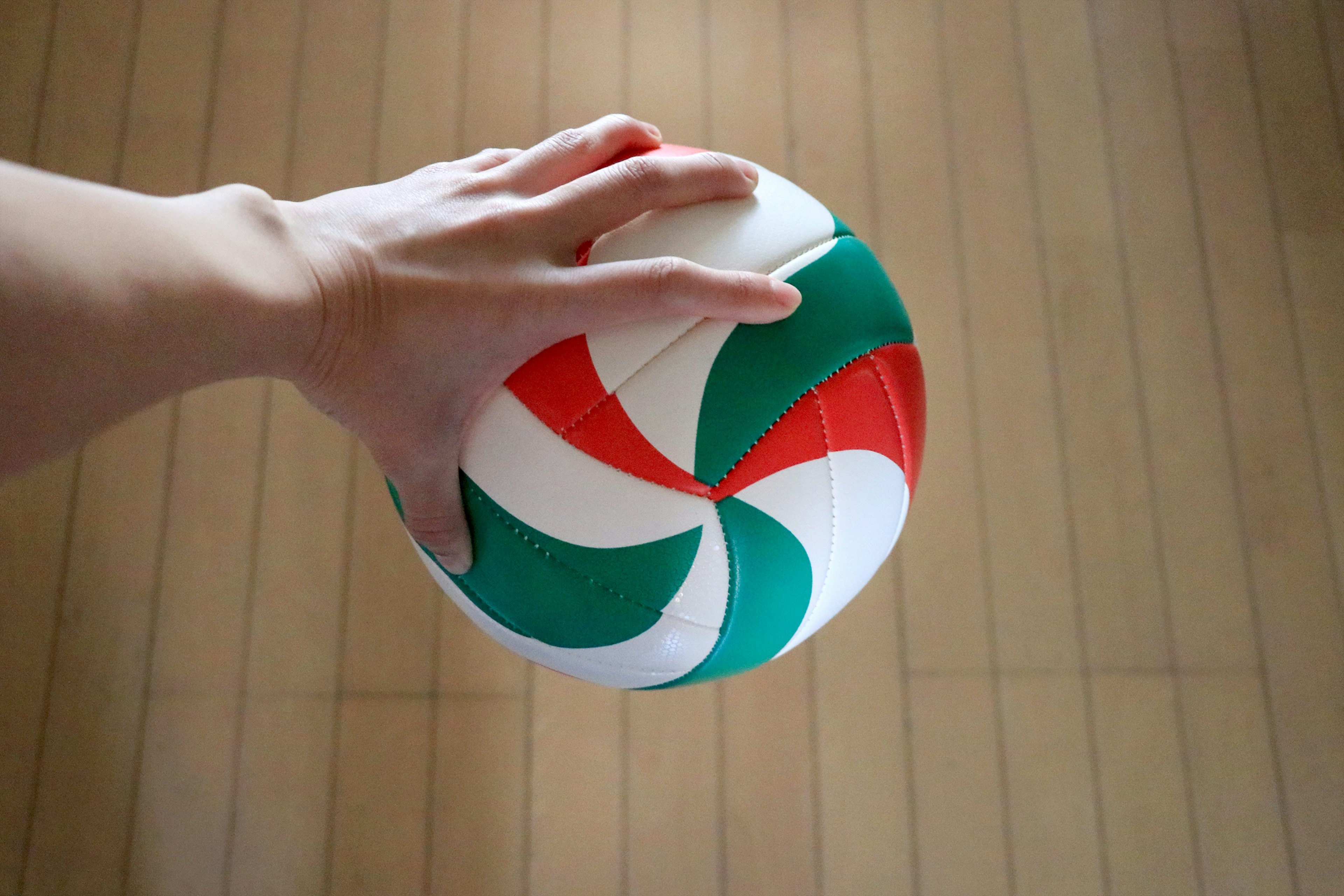 Colorful ball held in hand with wooden floor background