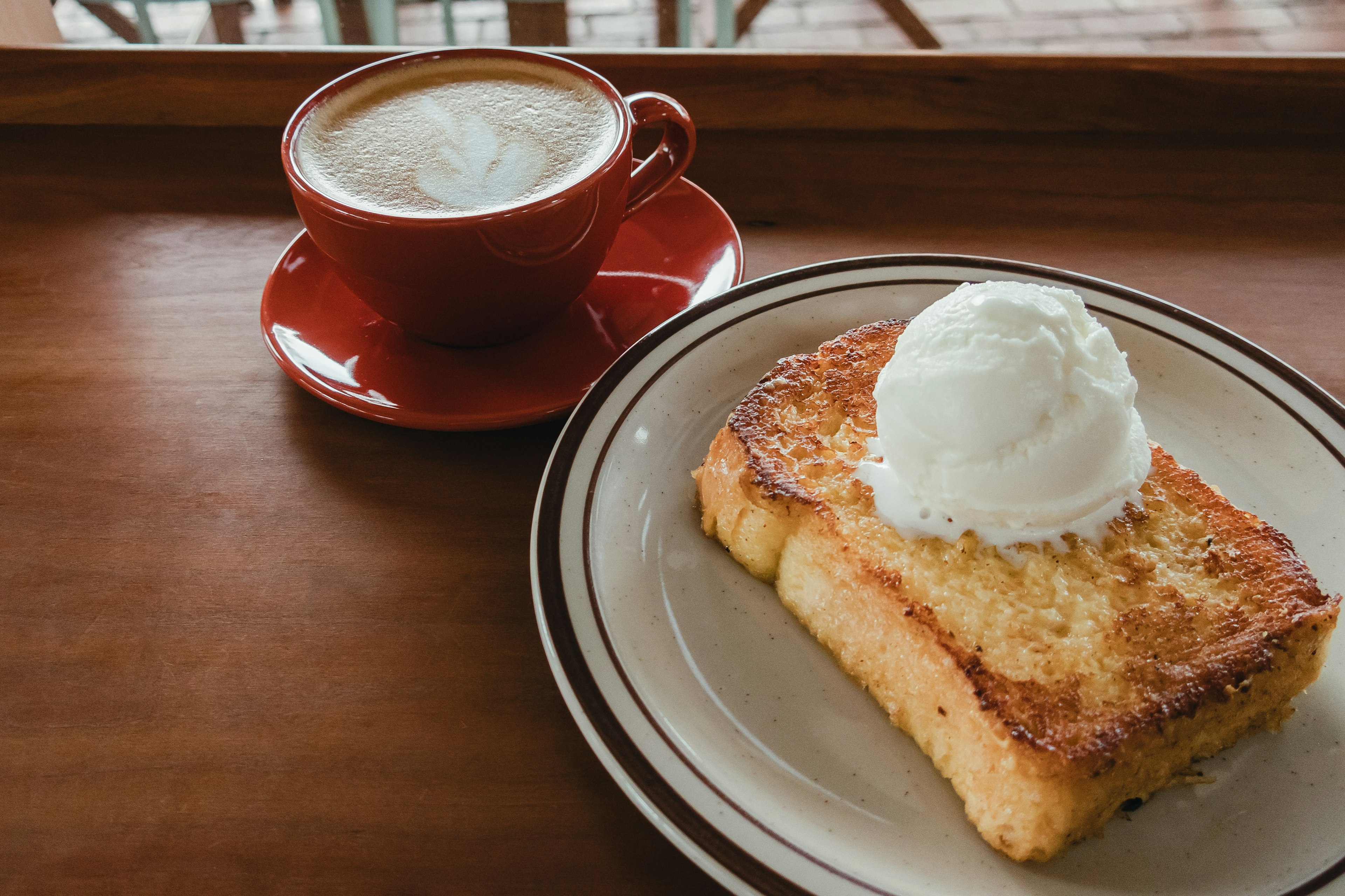 Image de pain perdu garni de crème glacée à côté d'une tasse de café