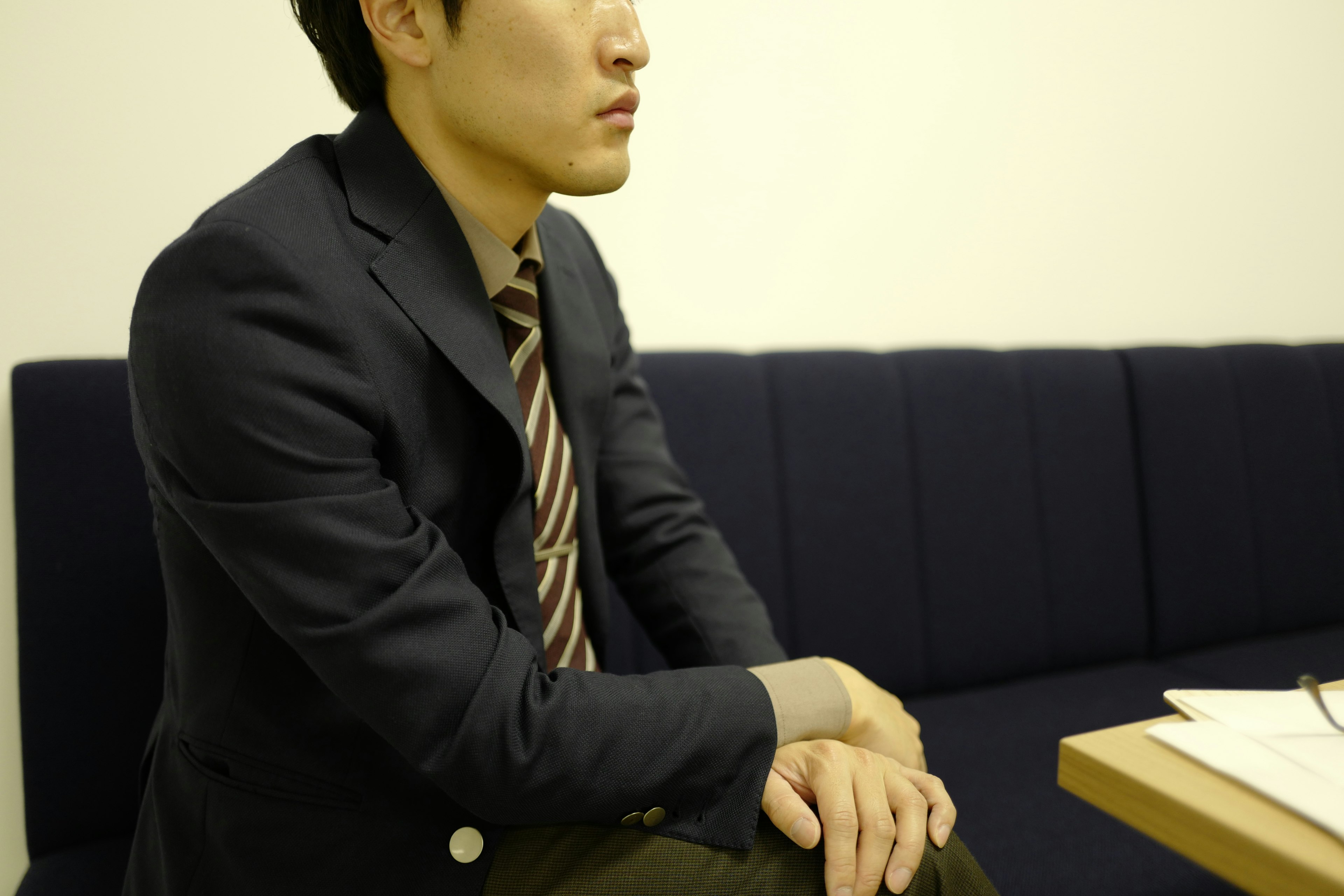 A man sitting on a blue sofa wearing a suit and tie