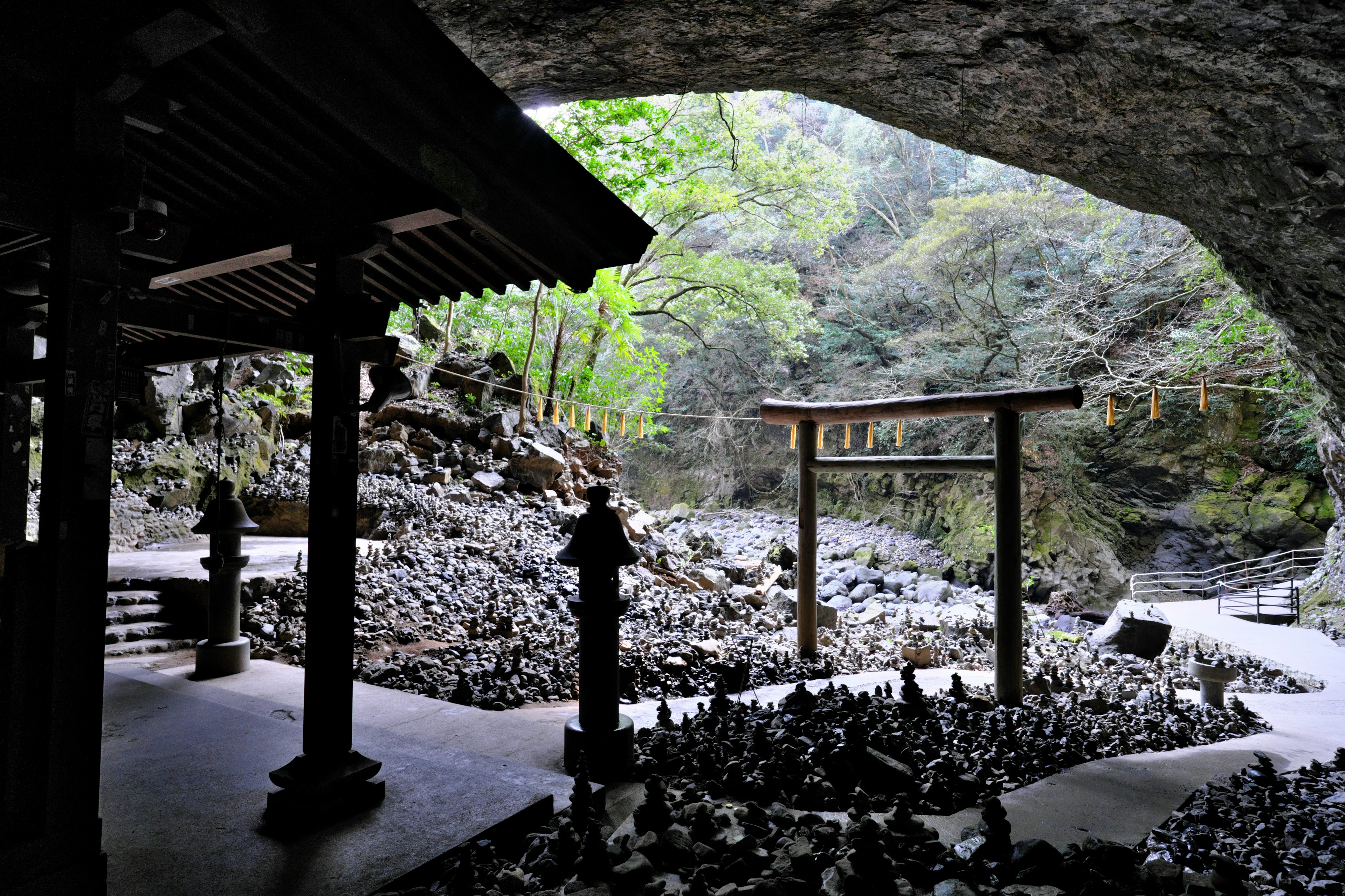 ทิวทัศน์ที่สวยงามของศาลเจ้าและประตูโทริอิในถ้ำที่ล้อมรอบด้วยธรรมชาติ